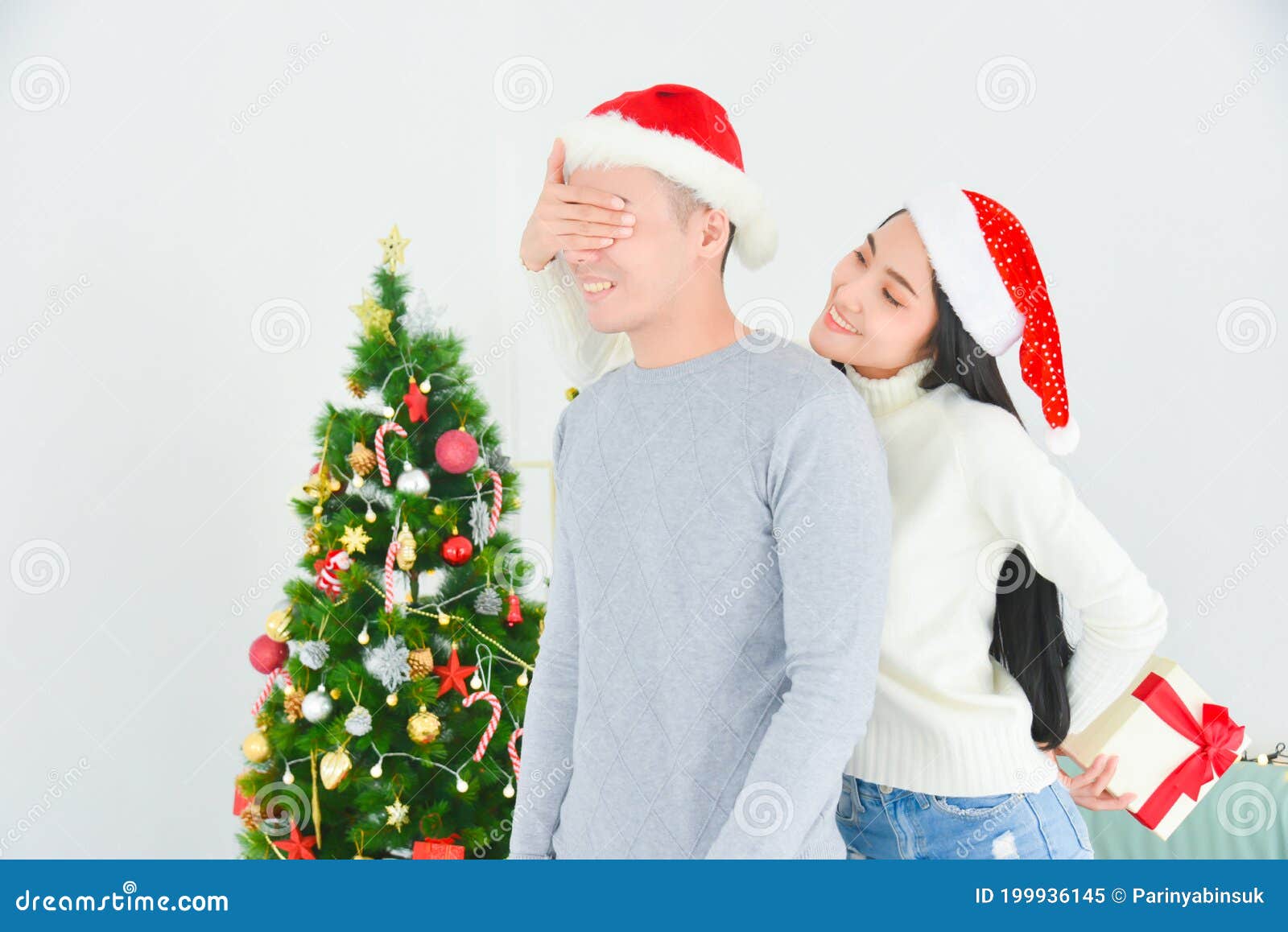 Jovem Que Cobria Os Olhos De Seu Namorado Fazendo Surpresa Com Uma Caixa De  Presentes. Perto Da árvore De Natal Em Casa Imagem de Stock - Imagem de  sorrir, caixa: 199936145