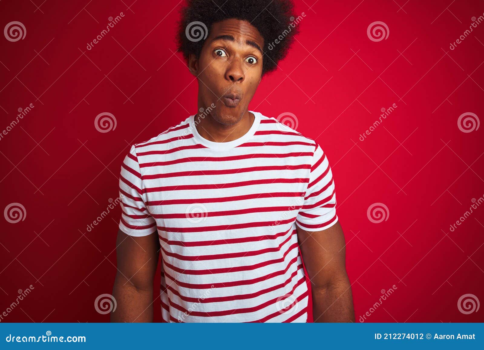 Joven Afroamericano Con El Pelo Afro Usando Camiseta A Rayas Sobre Fondo Rojo Aislado Haciendo 