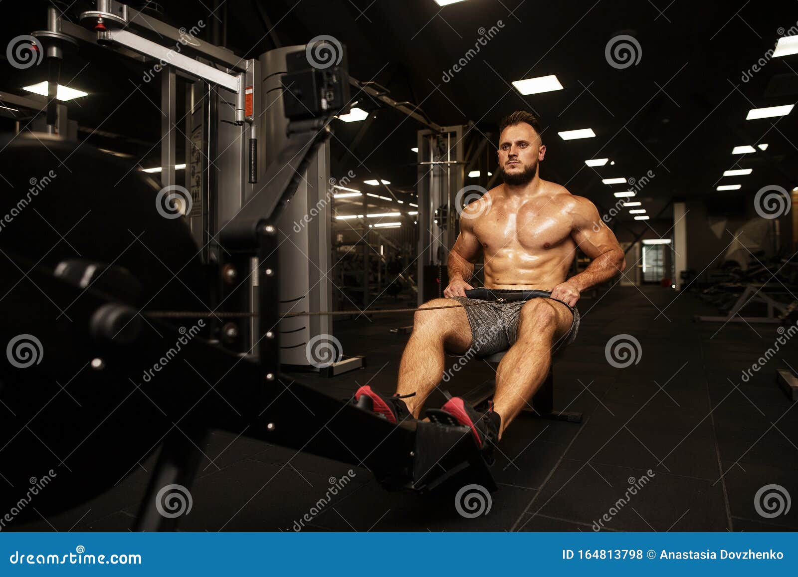 Hombre musculoso en la máquina de remo en el gimnasio