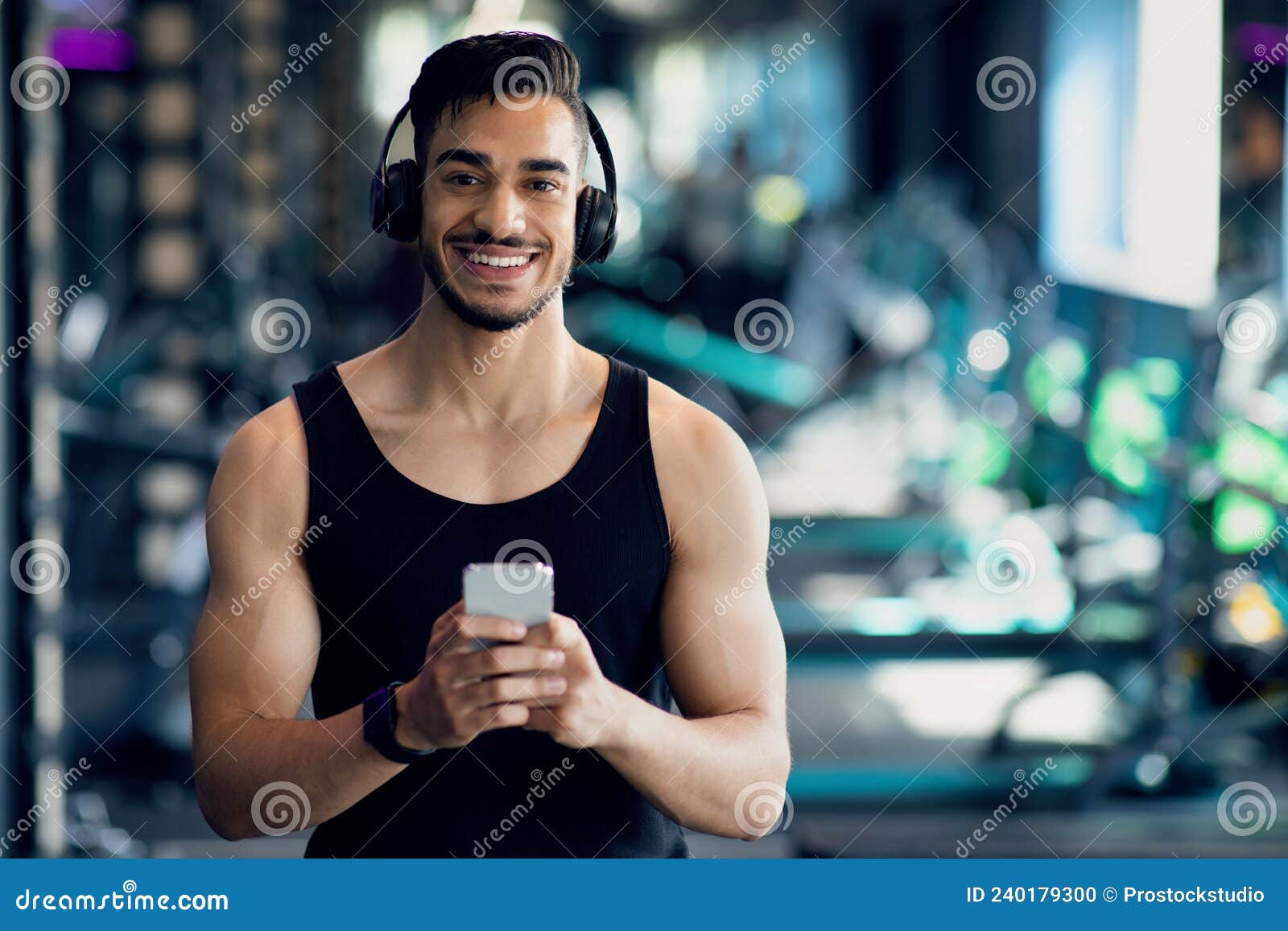 Deportista asiático en forma usando auriculares blancos y usando el  teléfono móvil para escuchar música mientras descansa o antes de correr  haciendo ejercicio en el gimnasio concepto de gimnasio deportivo saludable