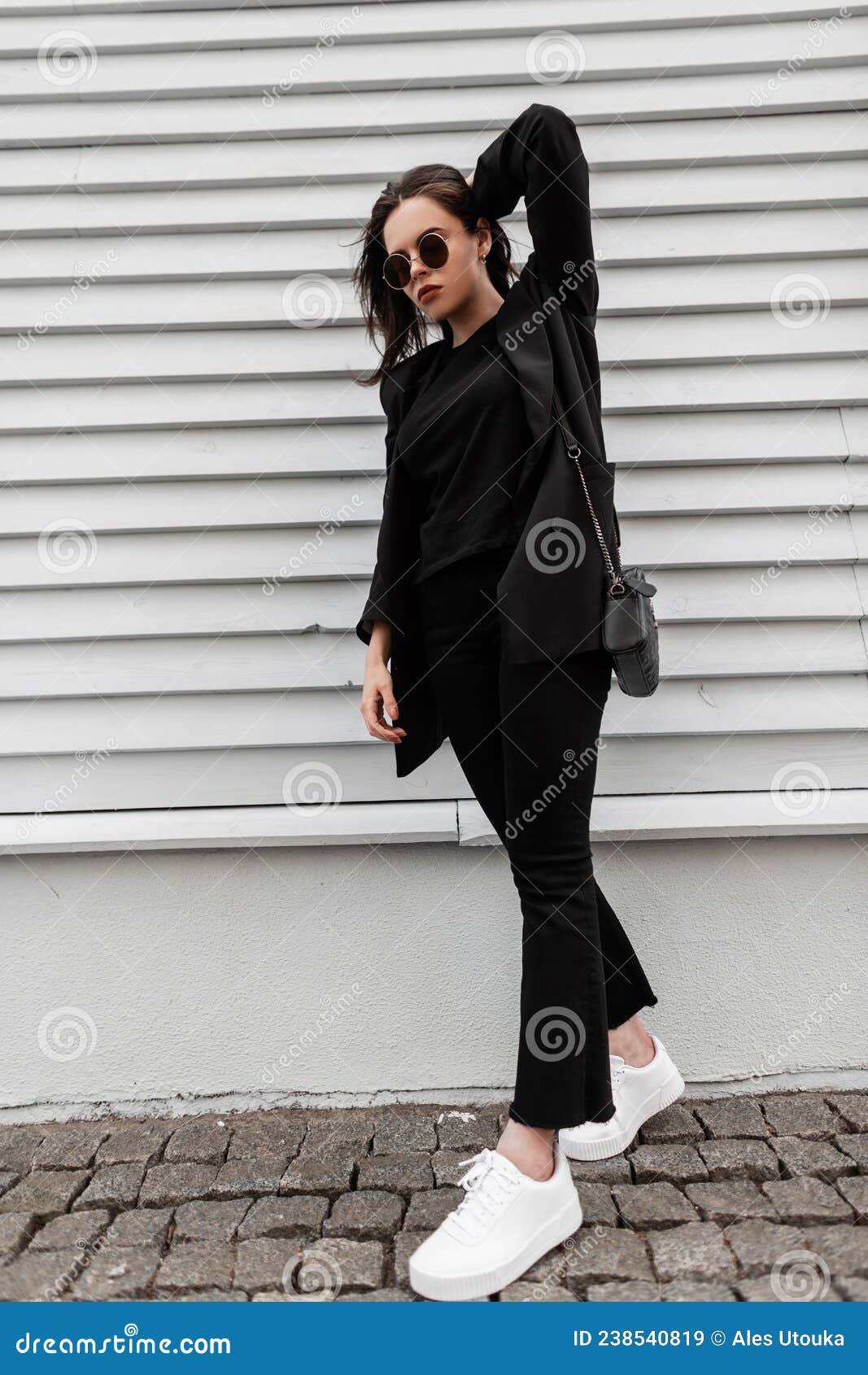 Joven Elegante Con Ropa De Moda De Negra Con Gafas De Sol En Zapatillas De Moda Blanca Bolsos De Cuero Cerca Imagen de archivo - Imagen de zapatos: 238540819