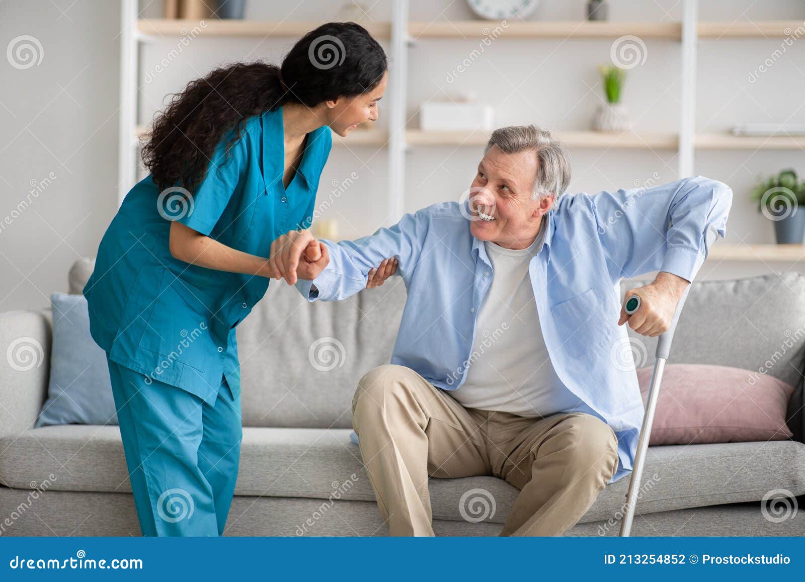 Joven Enfermera Ayuda Anciano Con Muletas Para Levantarse De Sofá En El  Interior Foto de archivo - Imagen de feliz, pensionista: 213254852