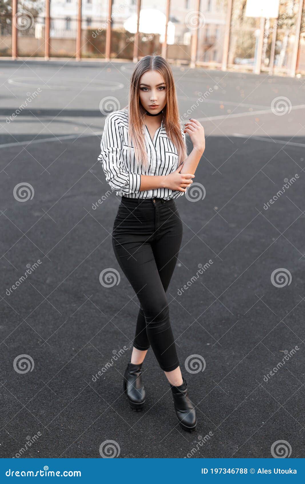 Joven Moderna Y Glamurosa Con Jeans Negros Y Elegantes En Una Blusa a Rayas Y Elegante Con Zapatos De Cuero De Posando En Un Foto de archivo - Imagen de moderno,