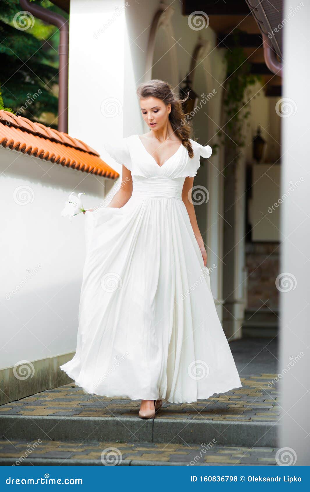 Joven Mujer Elegante Con Ramo De Boda Vestida Con Un Vestido Blanco Largo Y  Claro Que Camina Cerca De Una Casa Blanca Antes De La Foto de archivo -  Imagen de feliz,
