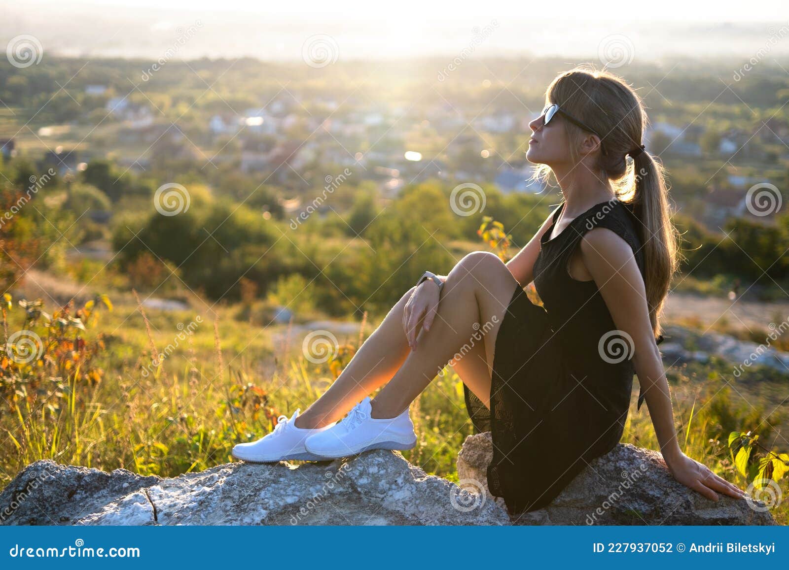 Joven Y Mujer Con Vestido Negro Corto Y Zapatos De Tenis Blancos Sentados En Una Roca Relajante Al Aire Libre En La Noche Foto de archivo - Imagen de hembra, estilo: