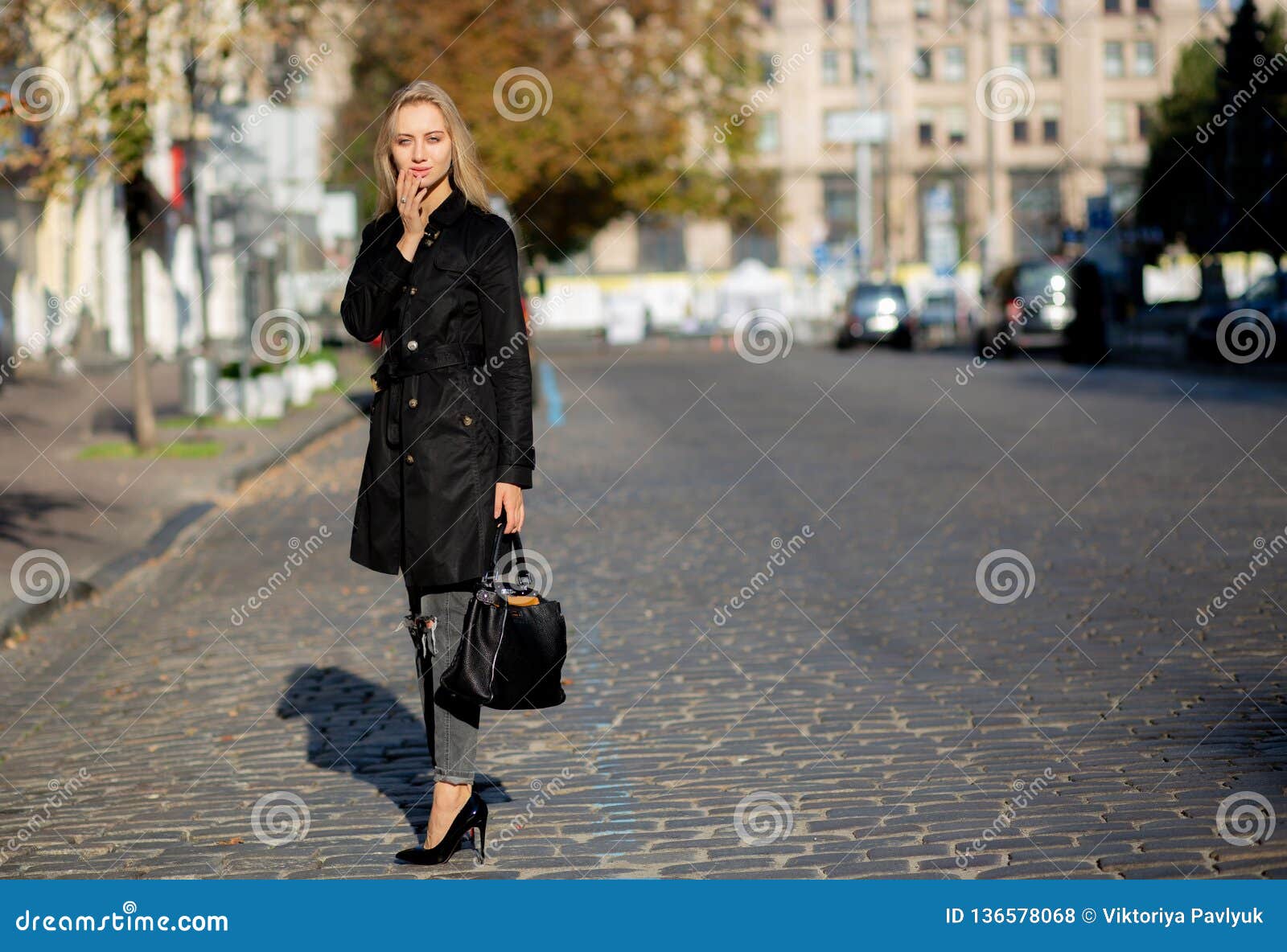Beautiful Fashionable Caucasian Blonde Woman With Big Breast Walking In The  Street, Wearing Round Sunglasses, Shiny Golden Dress, Black Stylish Coat  Holding Small Bag. Fashion Urban Spring Photo. Stock Photo, Picture and
