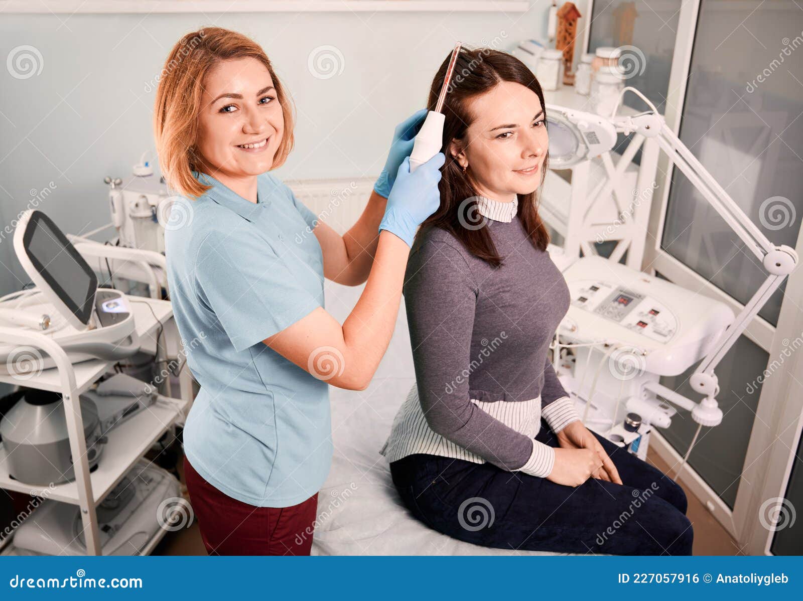 Cheerful Hair Specialist Brushing Woman Hair with Laser Device. Stock Photo  - Image of doctor, clinic: 227057916