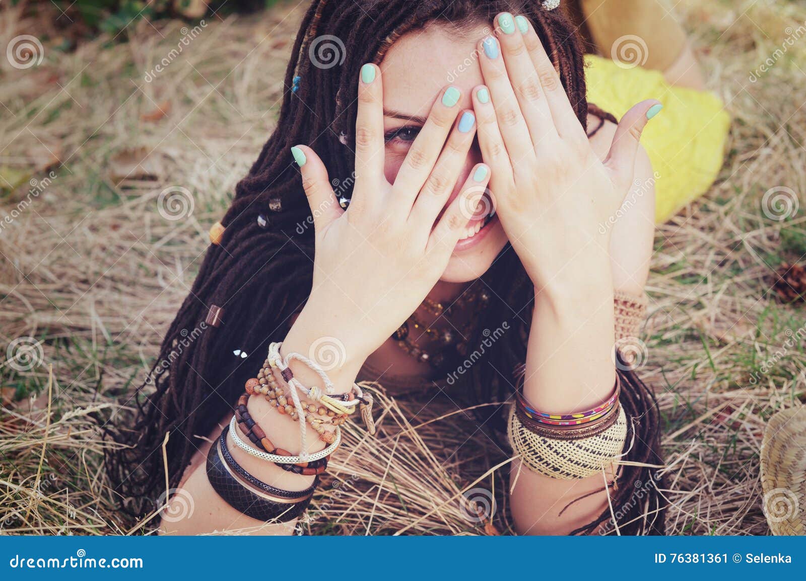 joyful indie style woman with dreadlocks hairstyle, have a fun closing her face with a hands