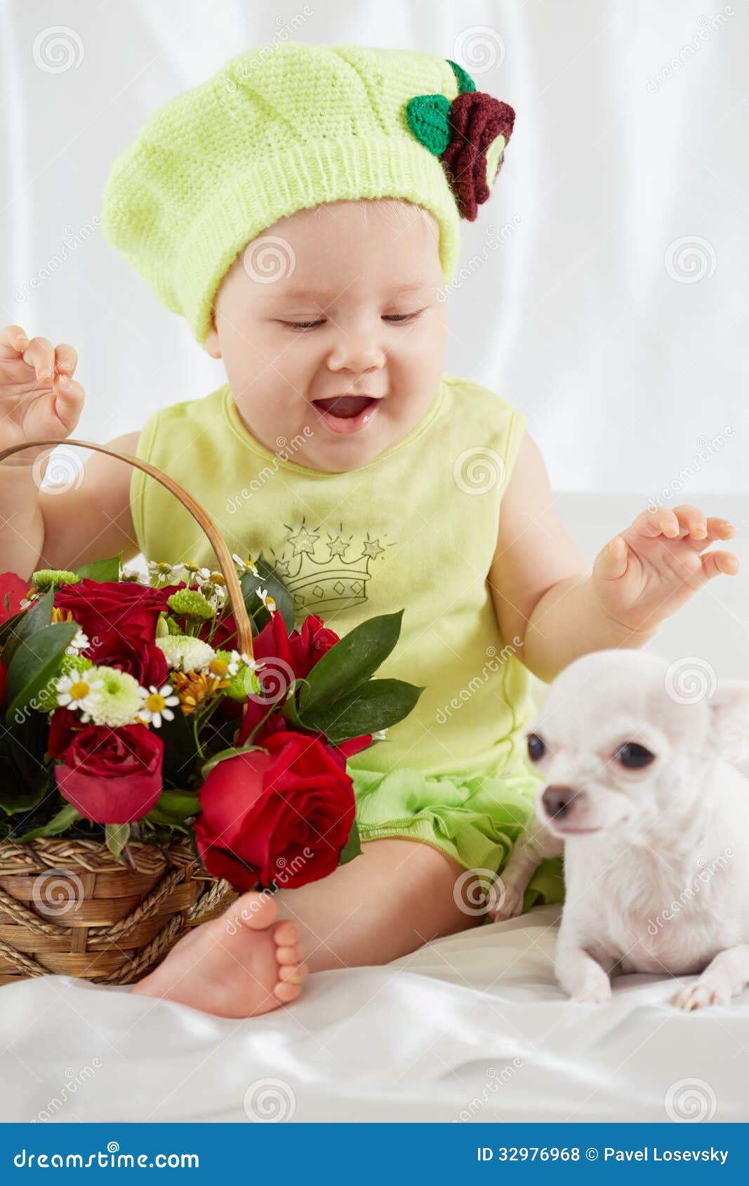 joyful little girl in greenish clothes and hat sits on bedding