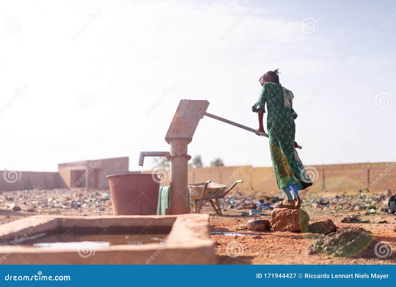 joyful native african young woman carrying healthy water in a village