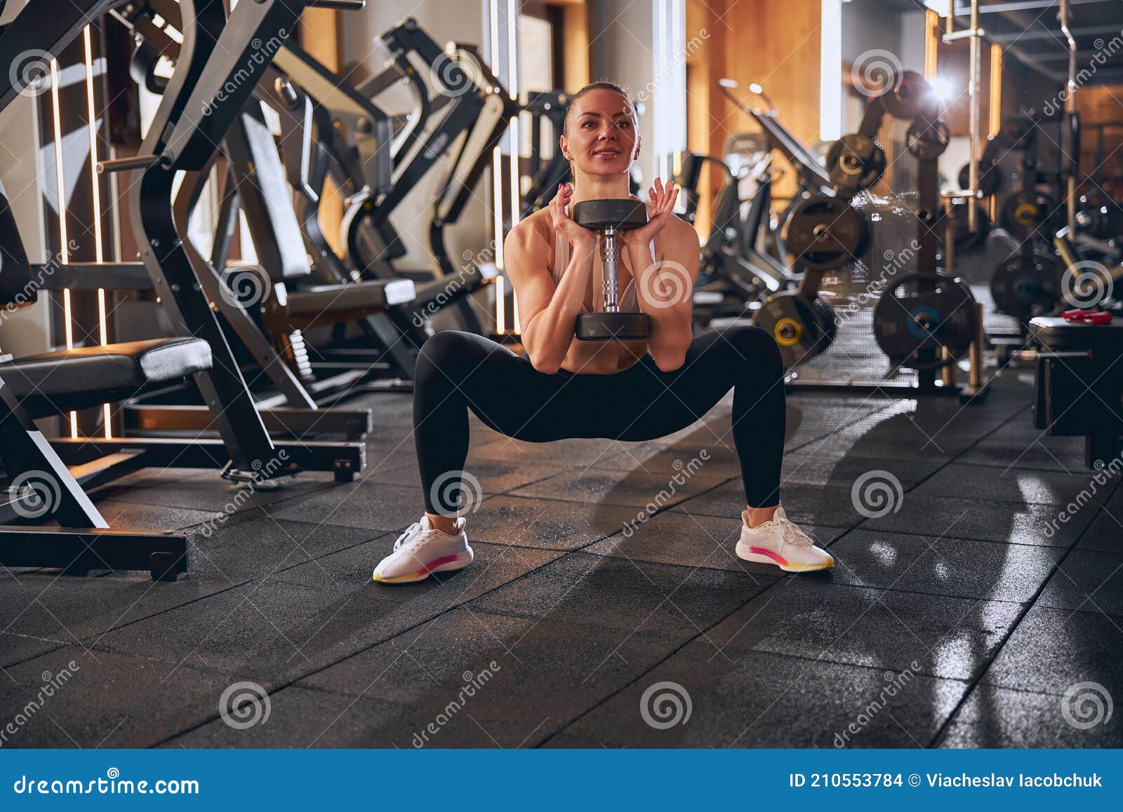 smiling fit female during strength workout in gym