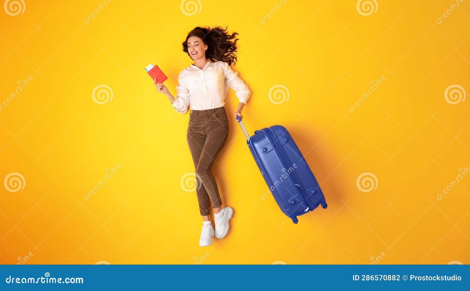 joyful young globetrotter lady with suitcase and tickets in studio