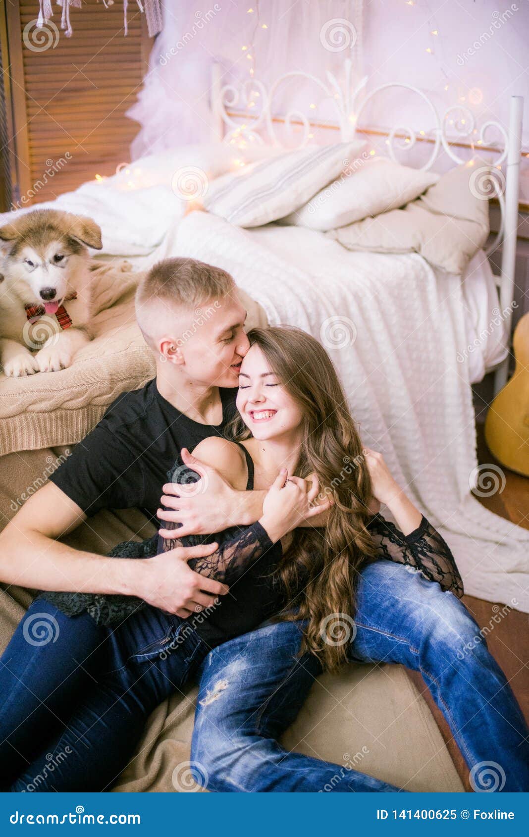 Joyful Young Loving Couple Sitting In The Bedroom While Expressing Love