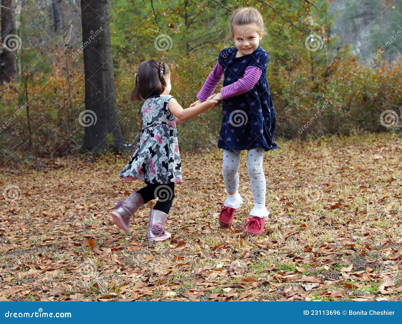 Juegos del otoño. Dos manos y oscilaciones del asimiento de las niñas en círculos. Están jugando a juegos al aire libre en las hojas de la caída.