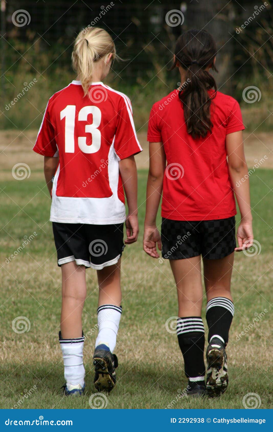 Jugadores de fútbol. Dos muchachas que se van al lado de uno a en uniformes del fútbol