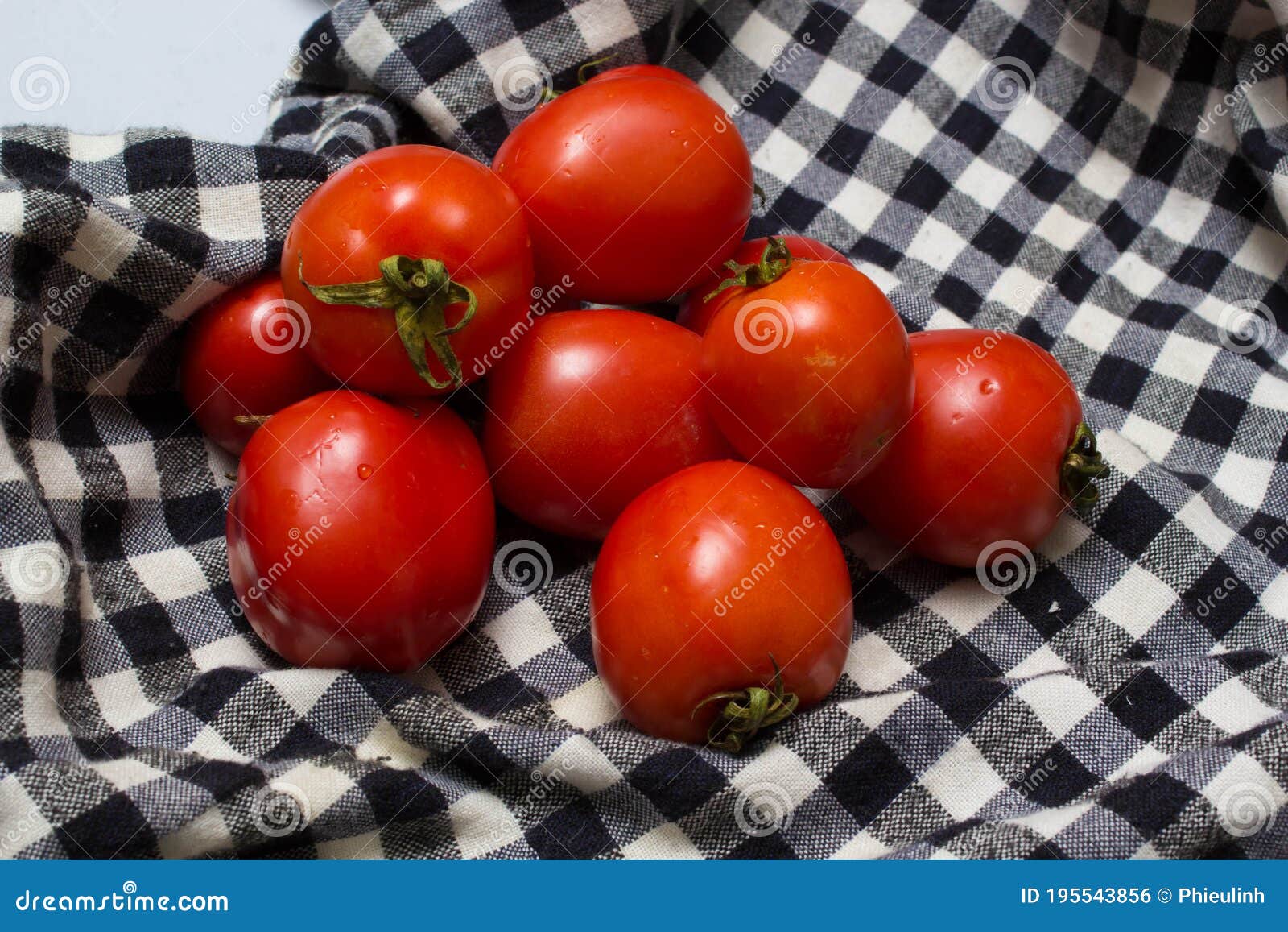 juicy red tomatoes in table cloth . caro background