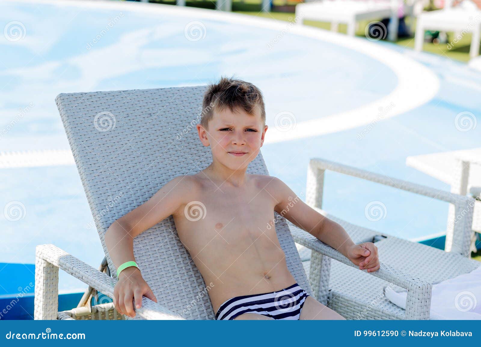Junge in Einem Badeanzug Auf Einem Regal Durch Das Pool Stockfoto