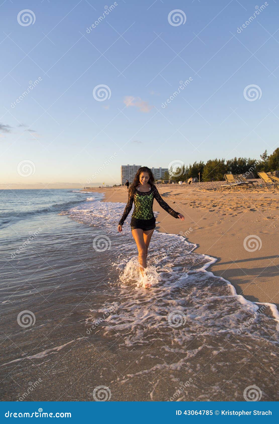 Junge Frau, die auf den Strand geht. Foto eines jungen Modells, das in den Ozean während des Sonnenaufgangs geht