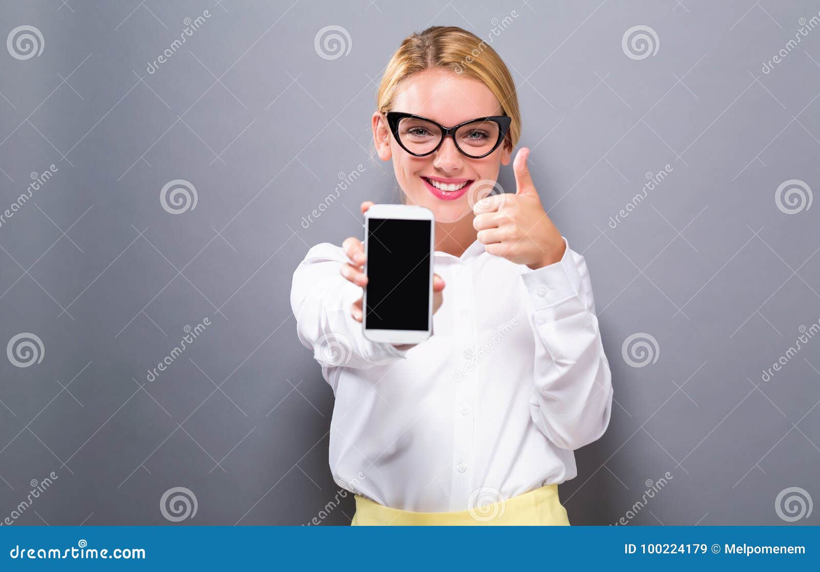 Junge Frau, die heraus ein Mobiltelefon hält