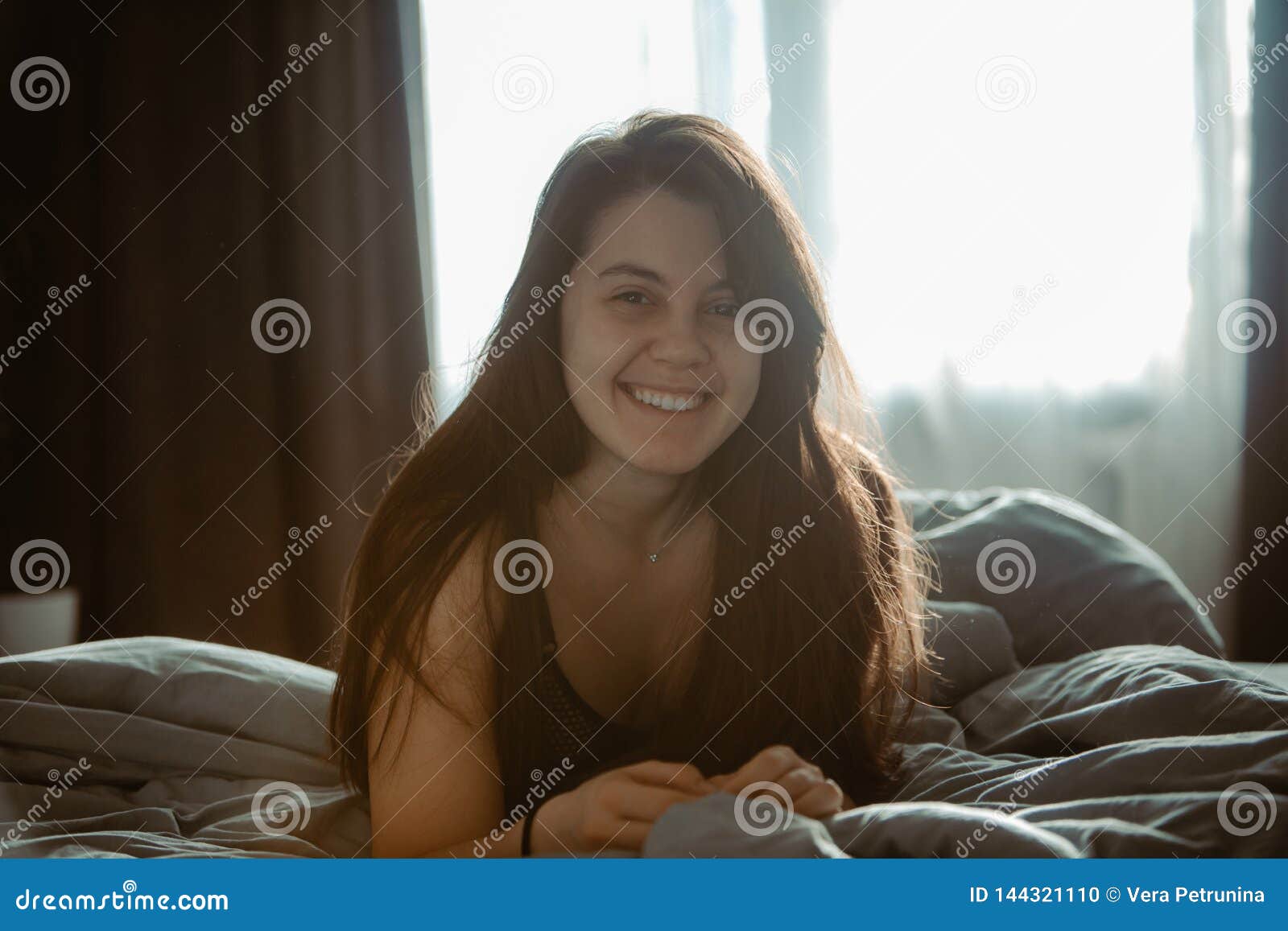 Young pretty woman in black bra sitting on bed. morning time. natural beauty