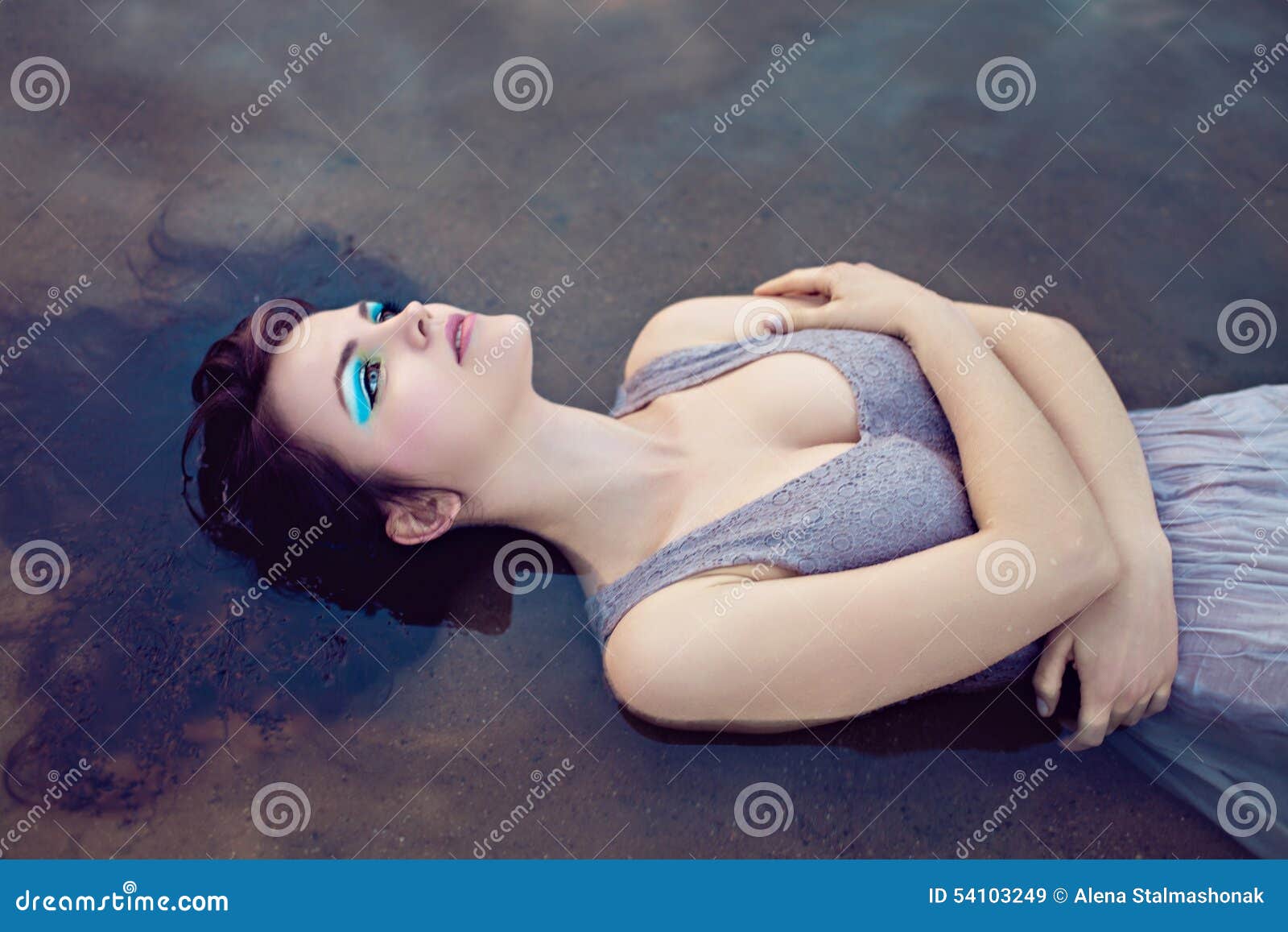Junge schöne ertrunkene Frau, die im Wasser liegt. Junge schöne ertrunkene Frau im grauen Kleid, das im Wasser liegt