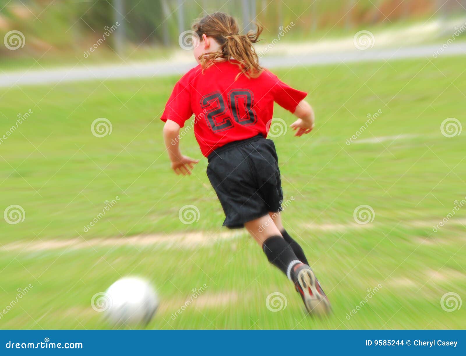 Junger Fußballspieler, der Kugel jagt. Junger Fußballspieler auf dem Feld, das bewegliche Kugel jagt