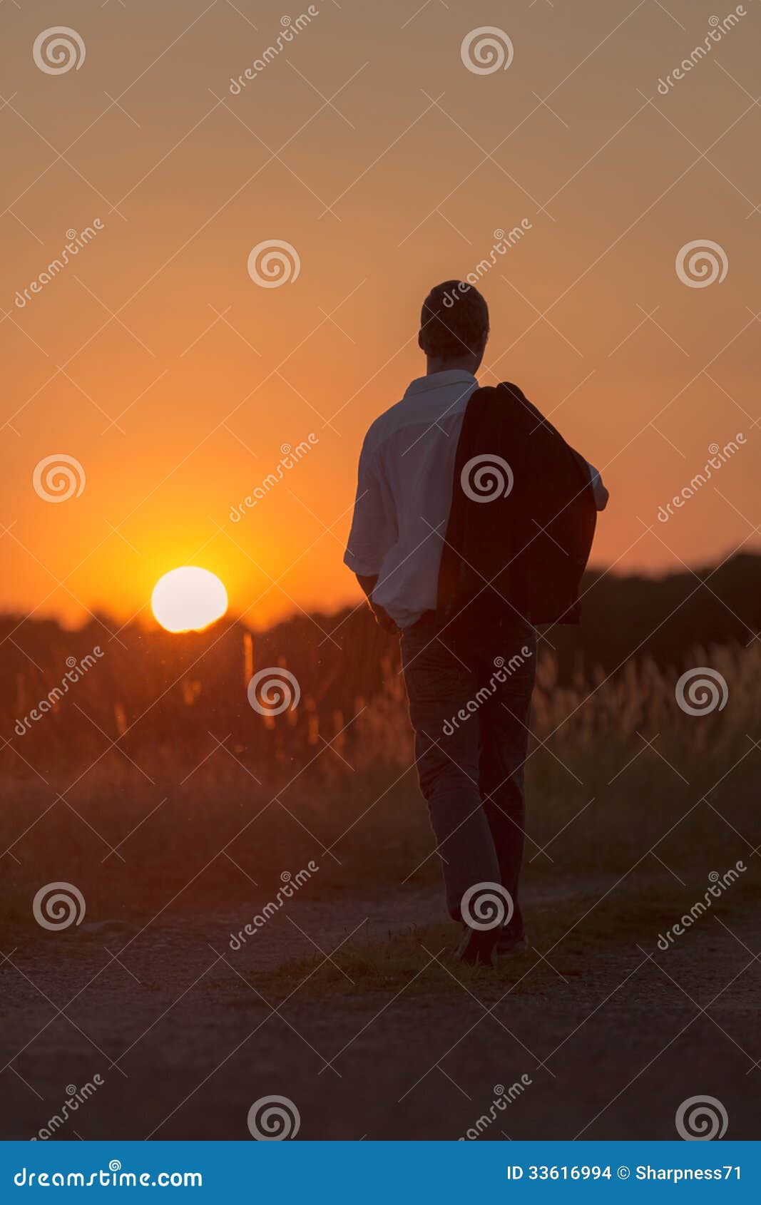 Junger Mann geht in Sonnenuntergang 1. Ein junger Mann geht einsam im Sonnenuntergang