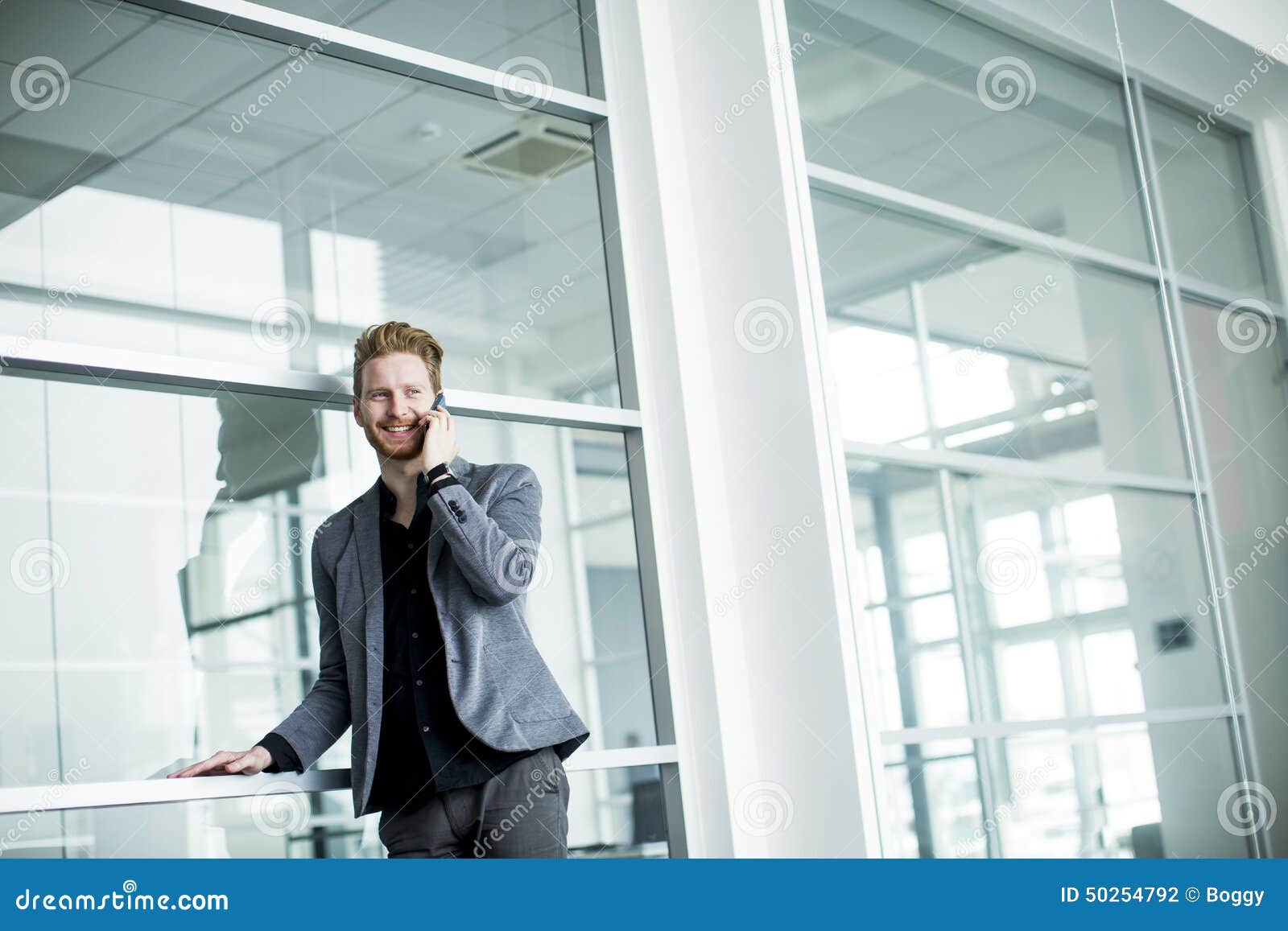 Junger Mann im Büro mit Handy