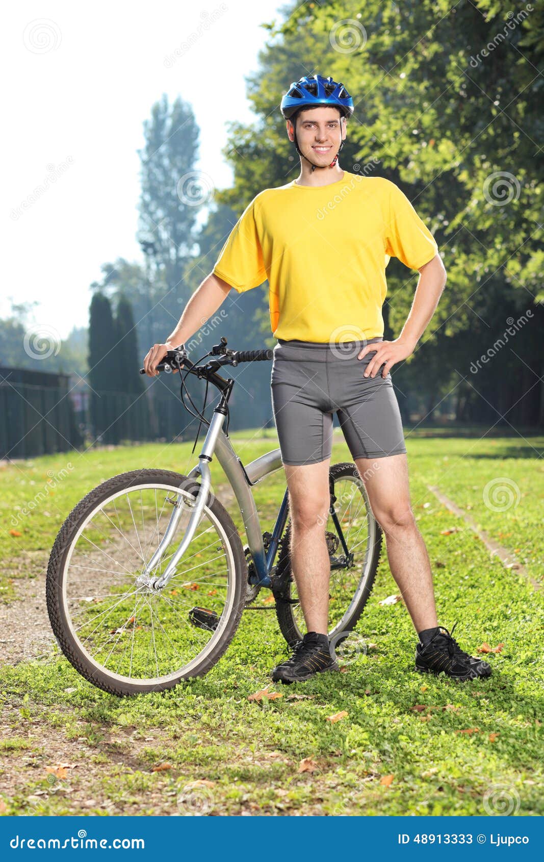 Junger Radfahrer, der mit seinem Fahrrad in einem Park aufwirft. Vertikaler Schuss eines jungen Radfahrers, der mit seinem Fahrrad in einem Park aufwirft
