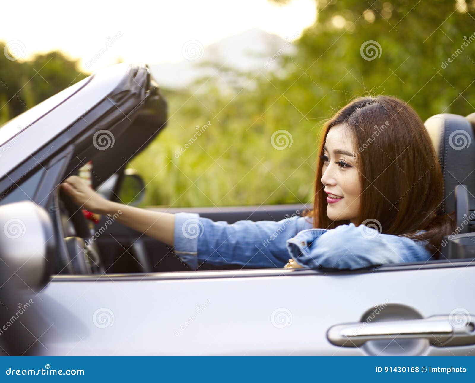 Junges asiatisches Frauenreiten in einem konvertierbaren Auto. Junges asiatisches Frauenreiten, in einem konvertierbaren Sportwagen, glücklich und im Lächeln