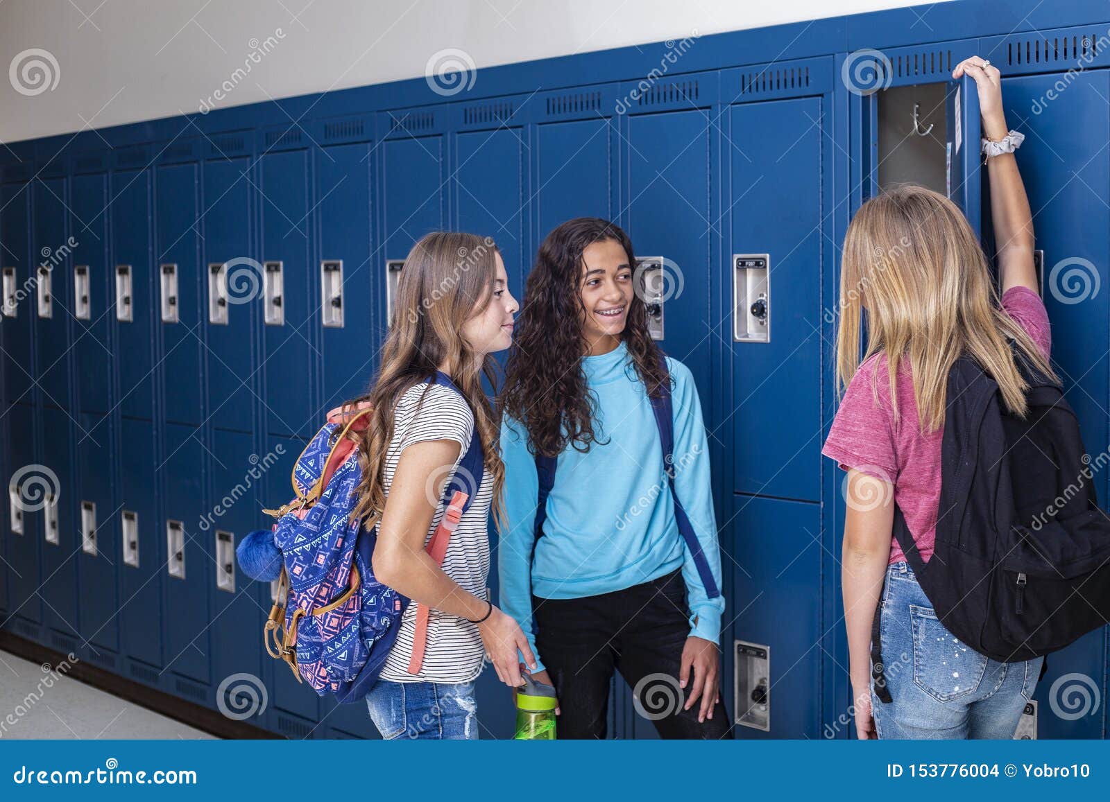 Junior High School Students Talking And Standing By Their Locker In A junior-high-school-students-talking-and-standing-by-their-locker-in-a