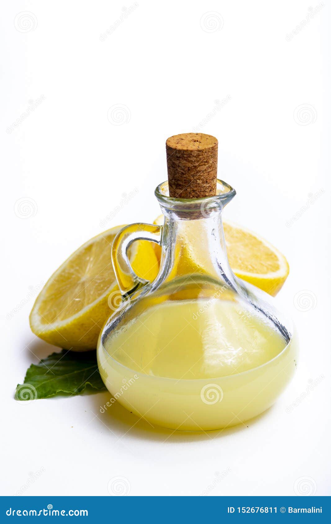 Jus de citron frais fait à partir des citrons siciliens jaunes mûrs utilisés pour faire cuire dans la bouteille en verre sur le plat en bois olive d'isolement sur le fond blanc