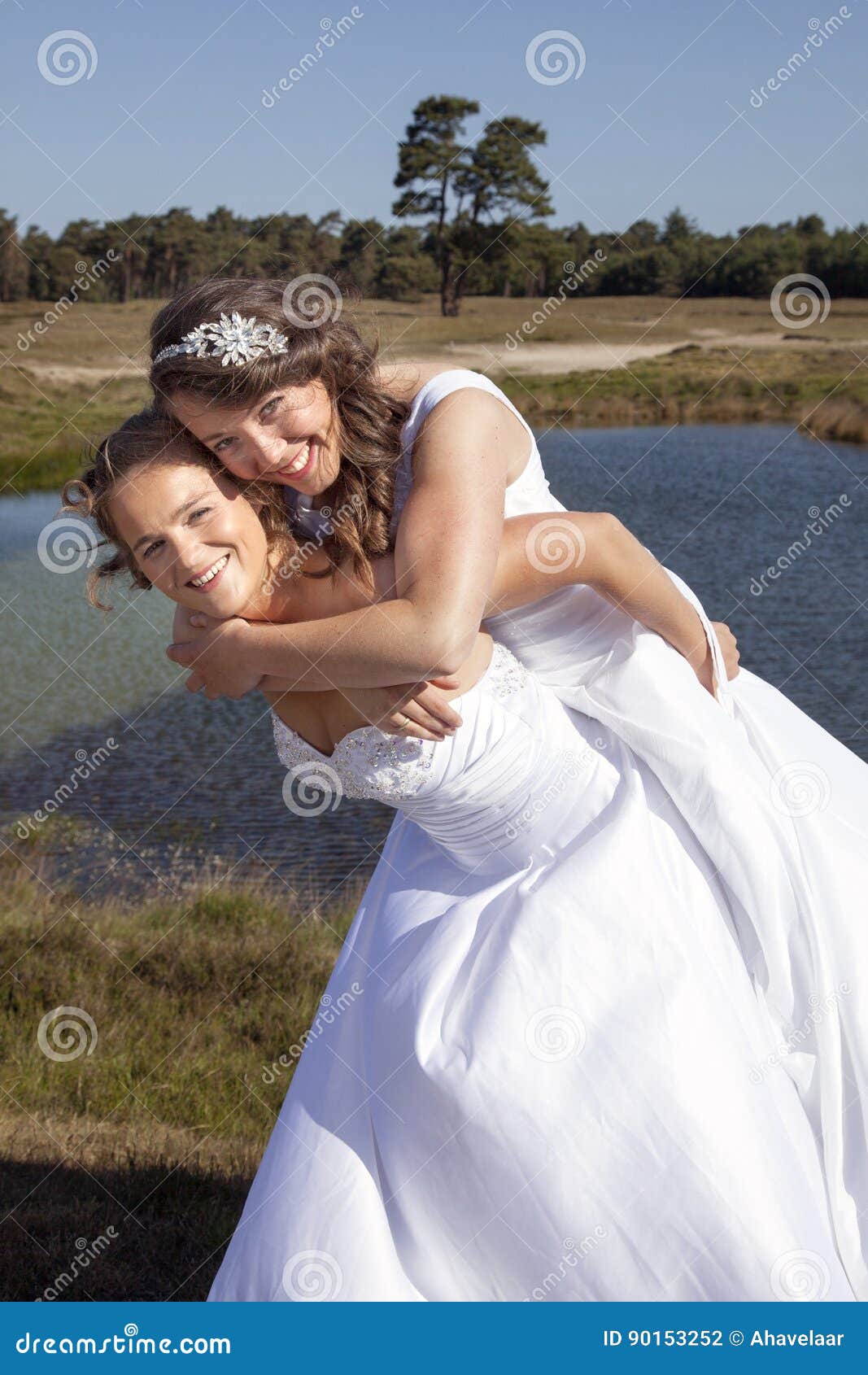 Just Married Happy Lesbian Couple in White Dress Embrace and Have Fun Near Small Lake Stock Photo image