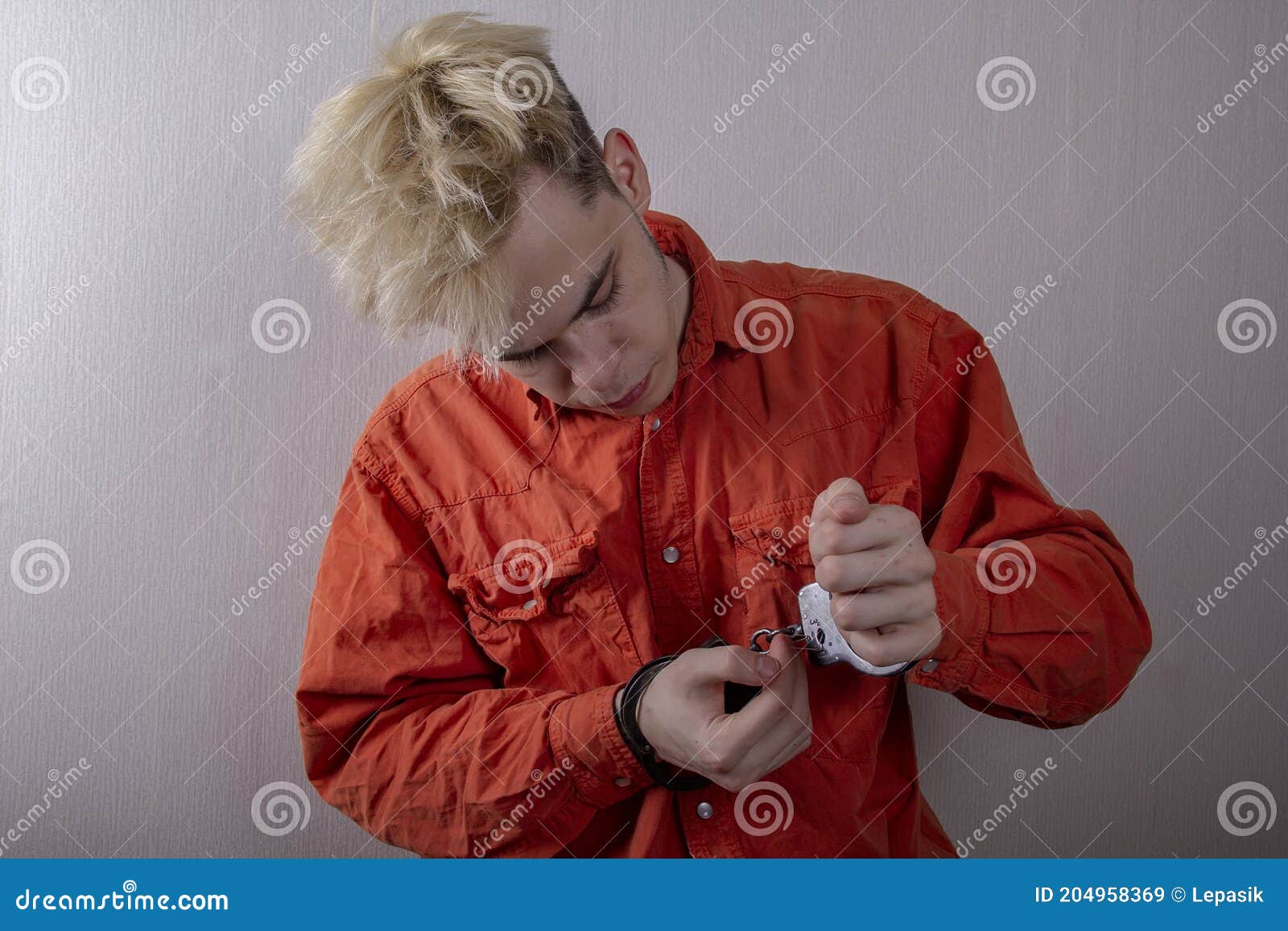 a juvenile delinquent tries to open the handcuffs with a paper clip.concept: attempt to escape from custody, opening locks, violat