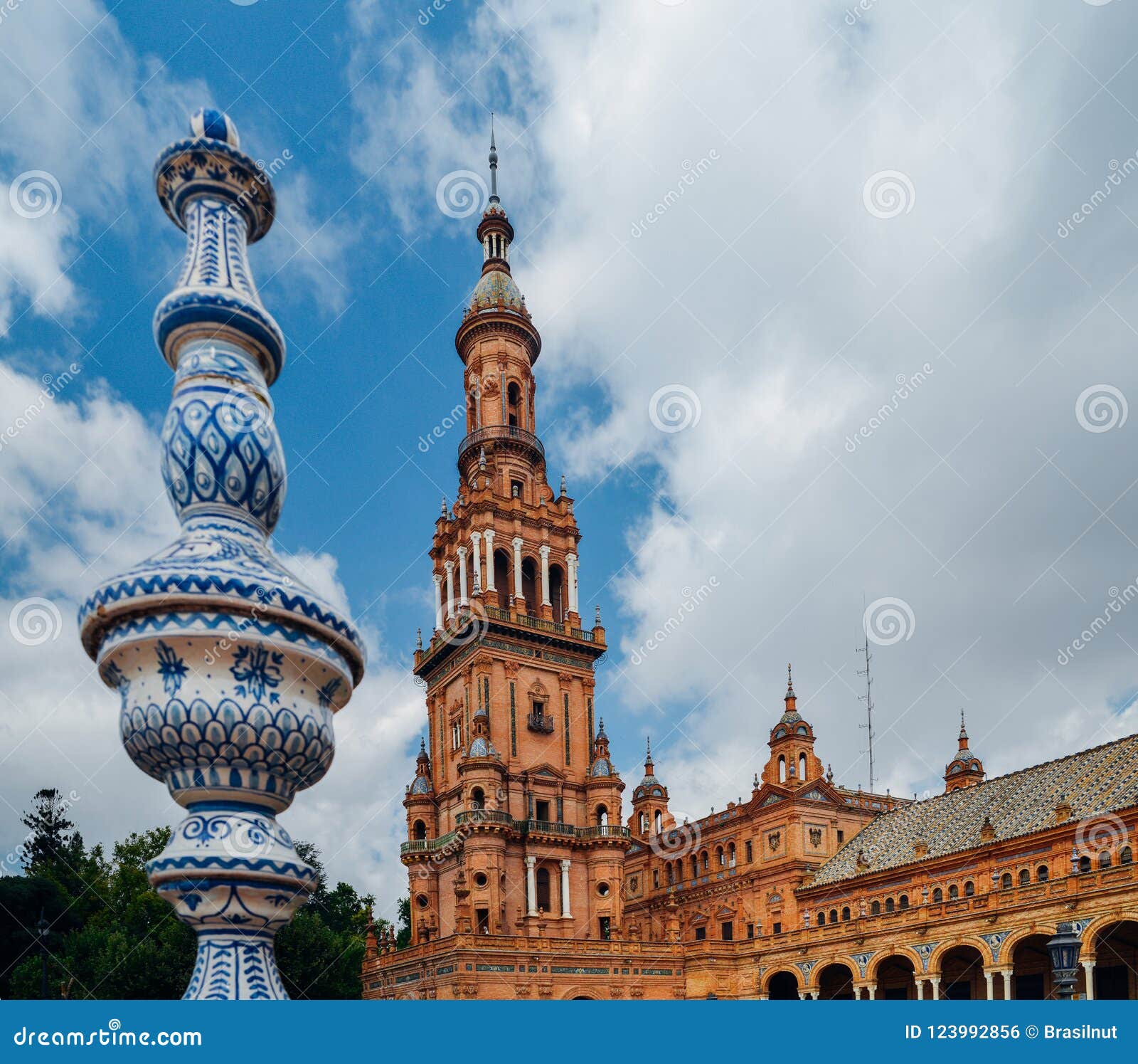 juxtaposition of blue and white ceramic azulejo tiles against one of the baroque sandstone tower at plaza de espana in seville, sp