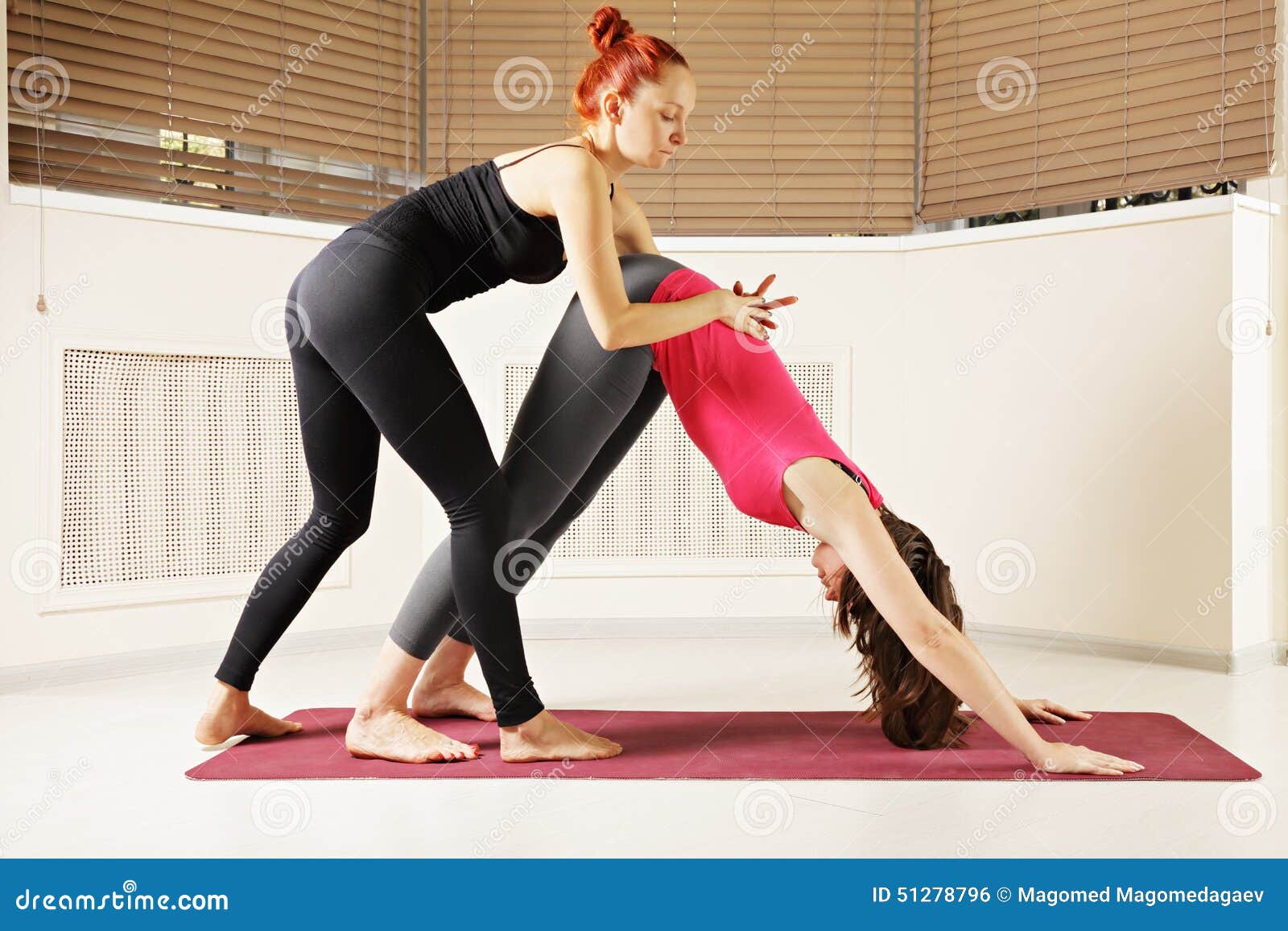 Young slim woman in the white hood sitting on the yoga mat with