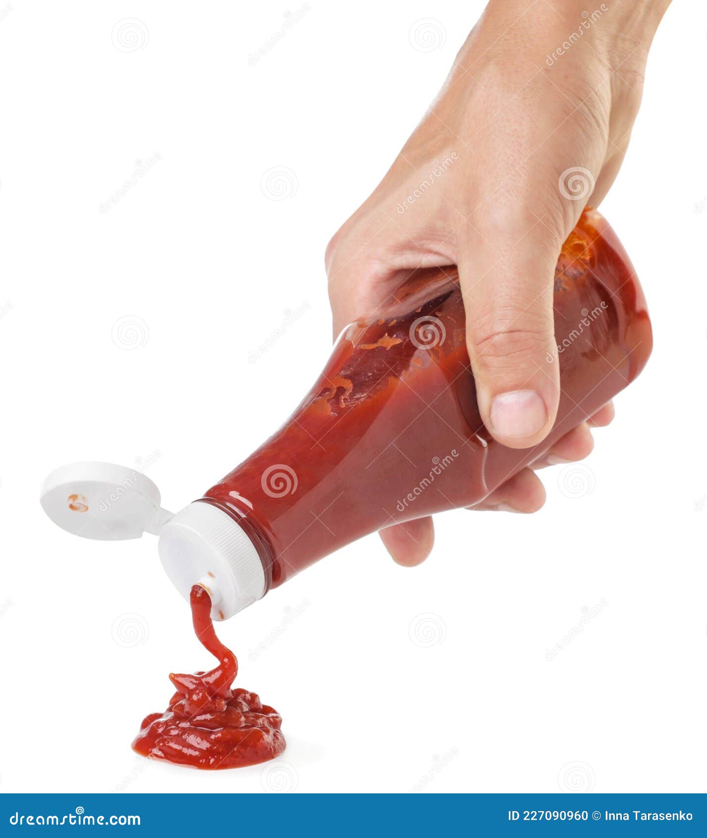 Ketchup Squeezes Out of a Bottle Hand on a White Background. Isolated