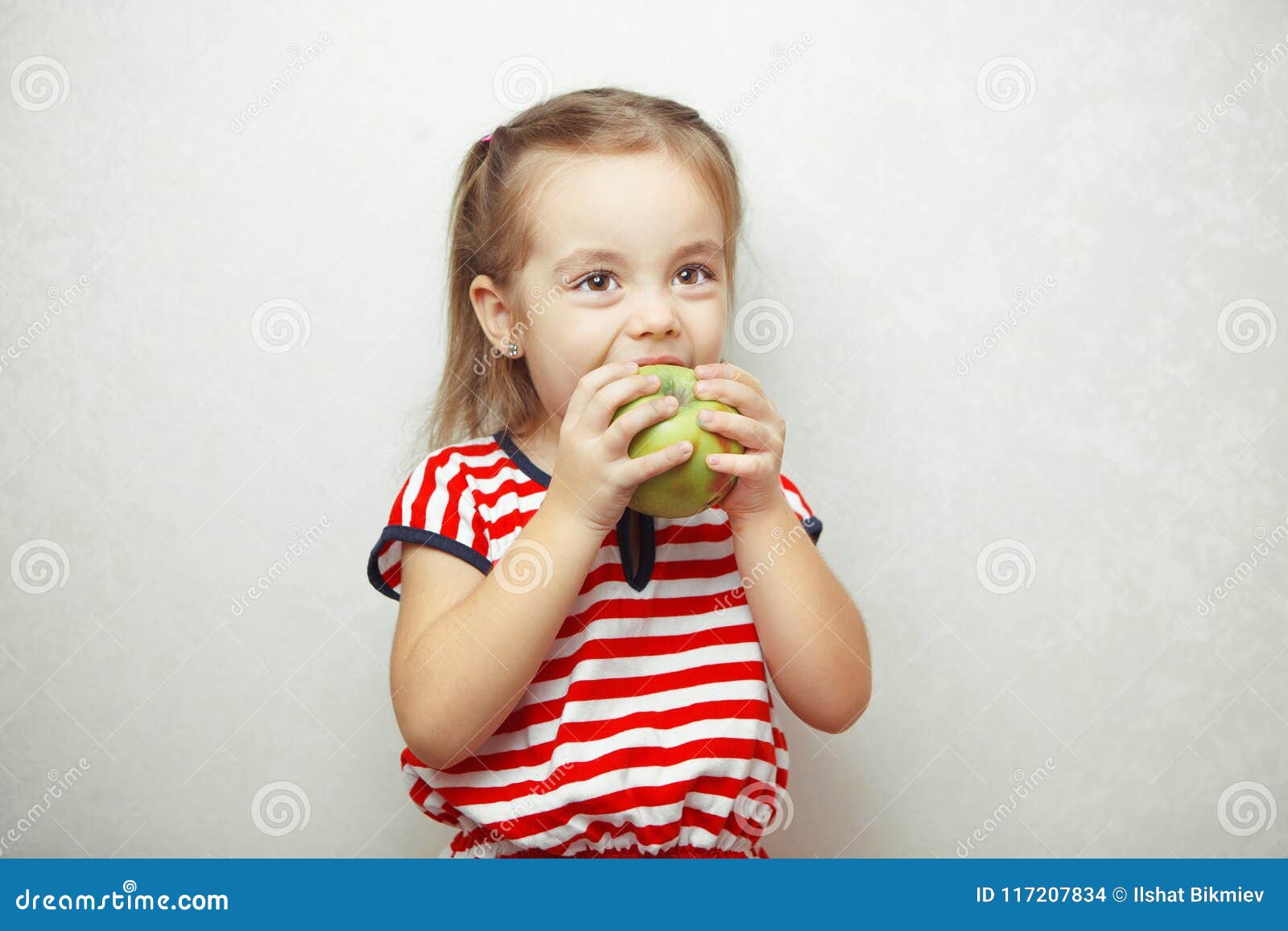 Kid with Cute Hairstyle Holding and Eating Green Apple Stock Photo - Image  of child, dress: 117207834