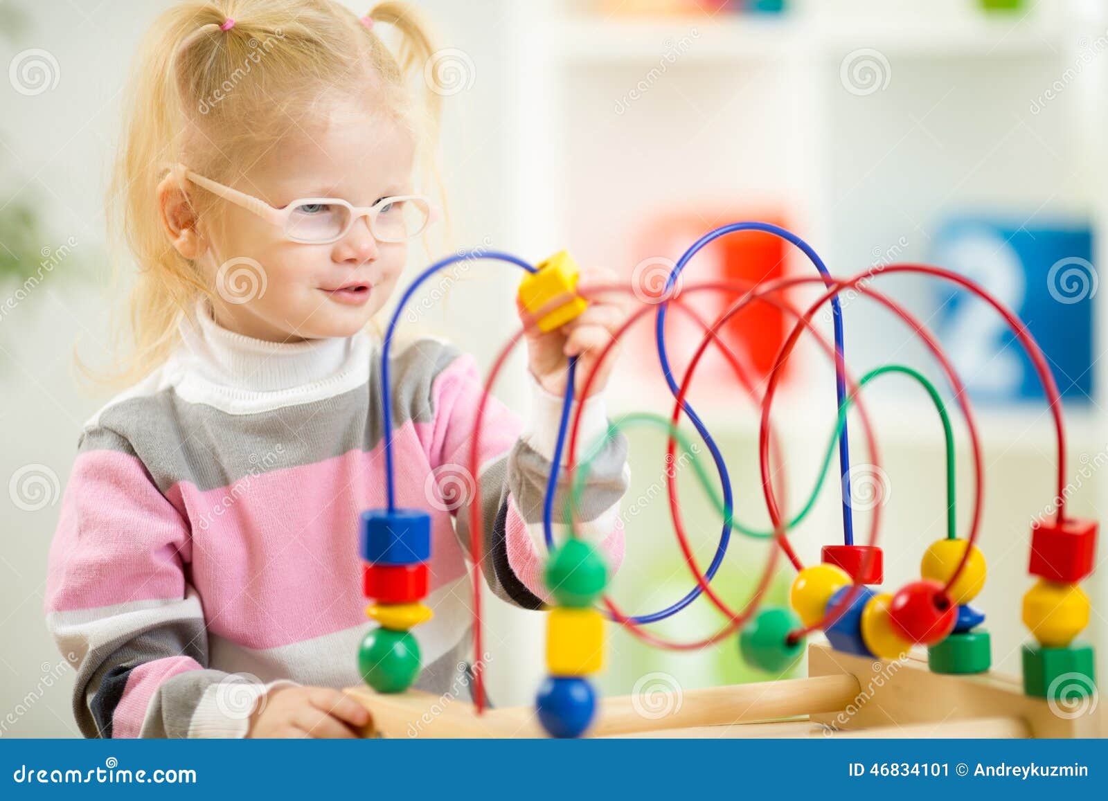 kid in eyeglases playing colorful toy in home