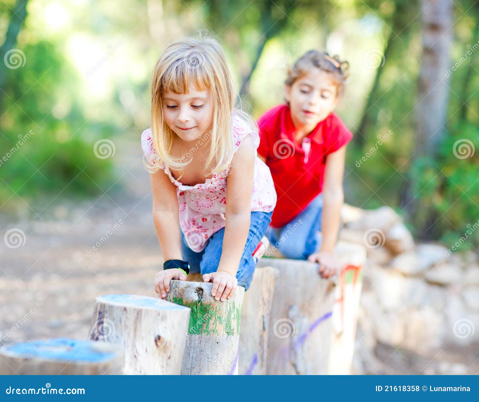 kid girls playing on trunks in forest nature