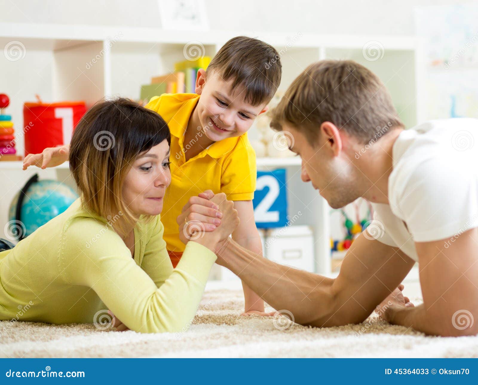 kid looks at his dad and mom competing in physical strength