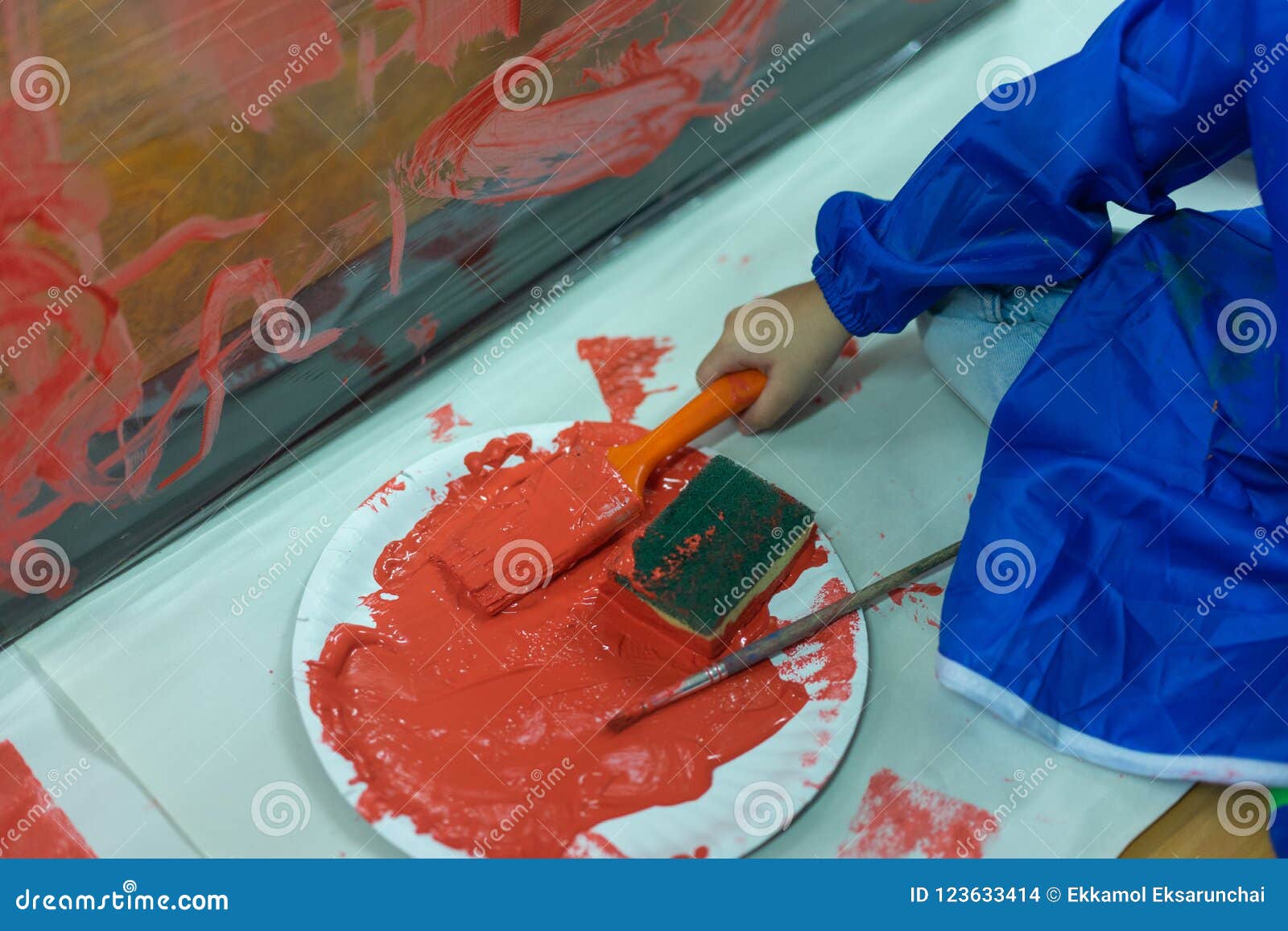 Kid is Painting the Plastic Wall with Red Color. Stock Photo Image of class, development