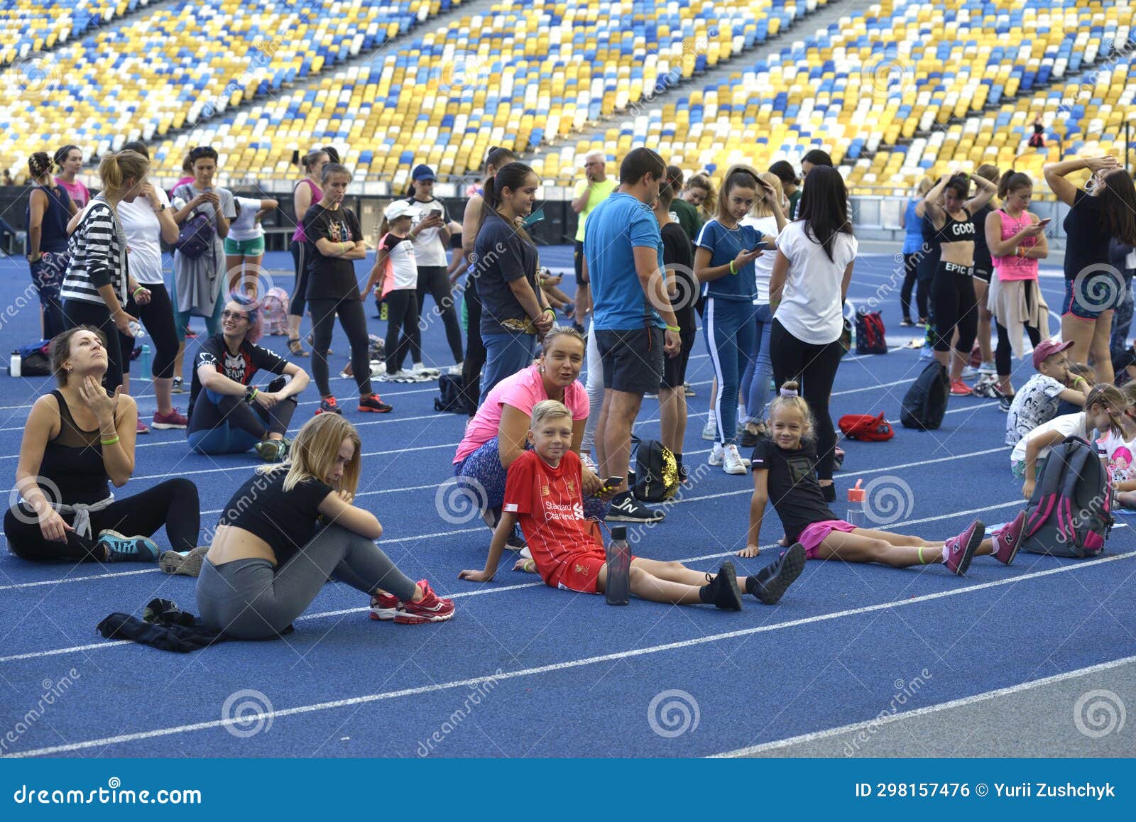 Kids and Adult in Tracksuits Sitting on a Track of a Stadium before ...