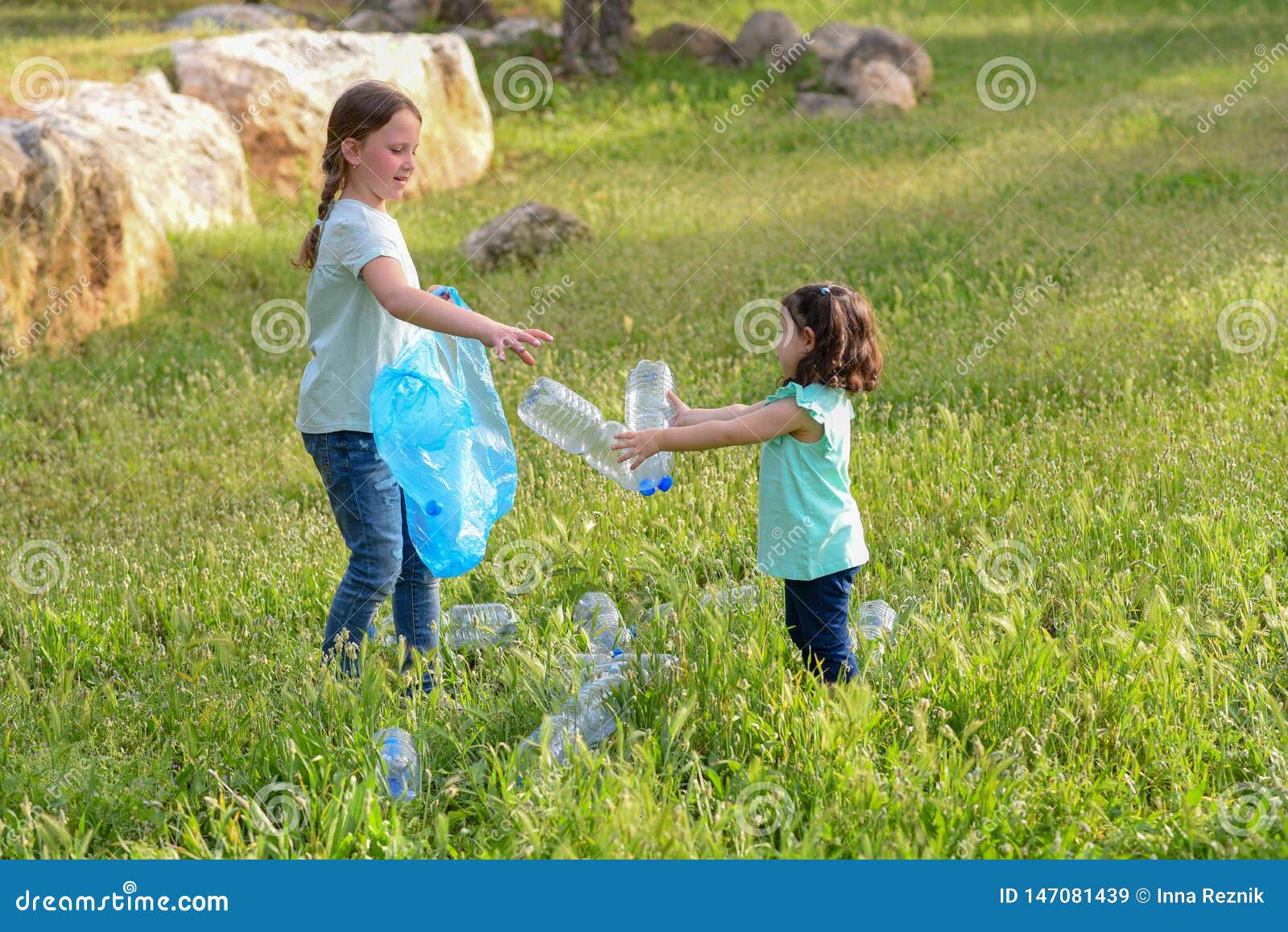 kids cleaning in park.volunteer children with a garbage bag cleaning up litter, putting plastic bottle in recycling bag.