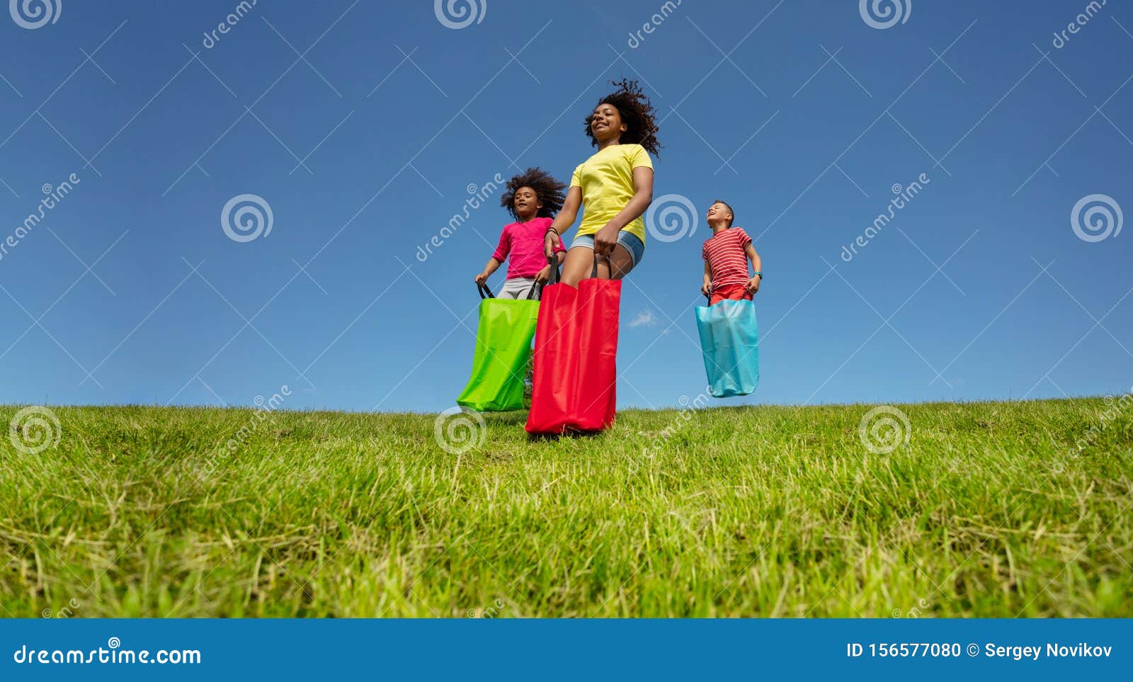 Kids Gunny Race in Bags Downhill on the Lawn Grass Stock Photo