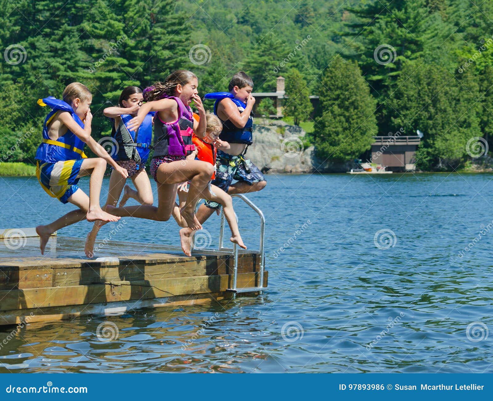 kids having summer fun jumping off dock into lake