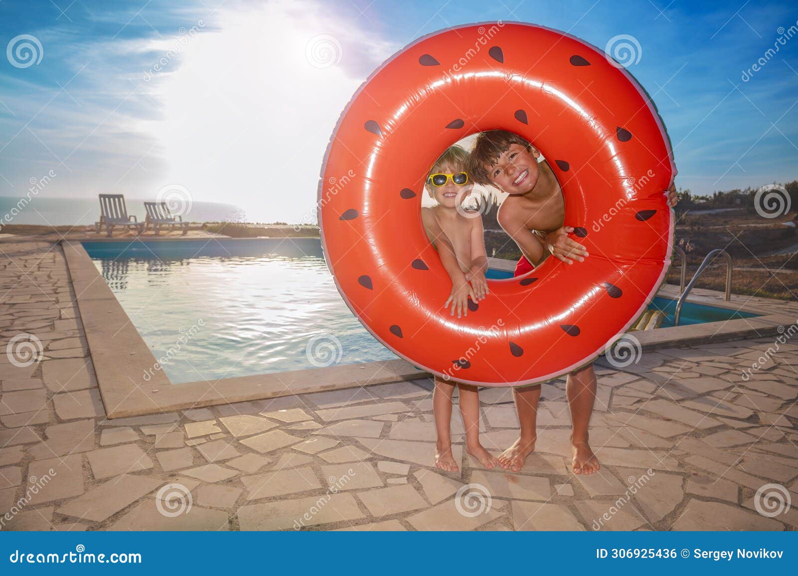 kids hold watermelon float at poolside look out from the hole
