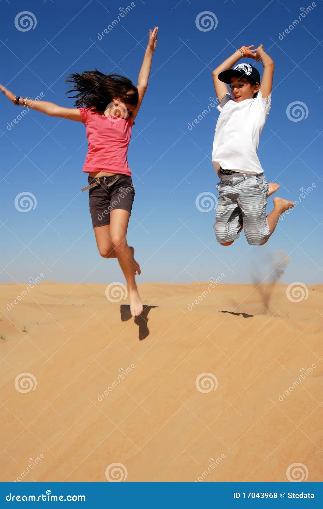 Teens Joyfully Leaping in Desert Dunes Under a Blue Sky, Reveling in Playful Moments and