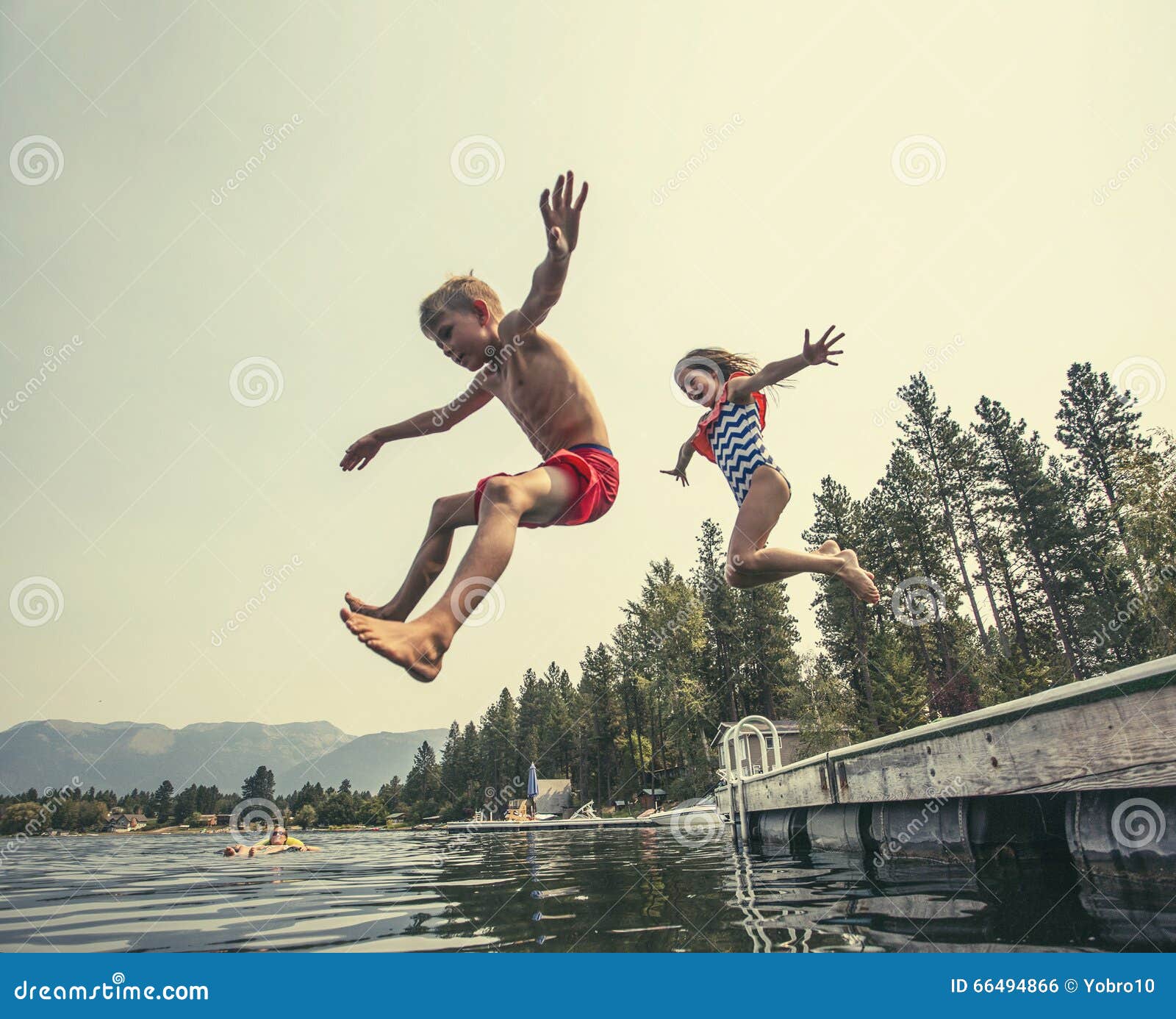 kids jumping off the dock into a beautiful mountain lake