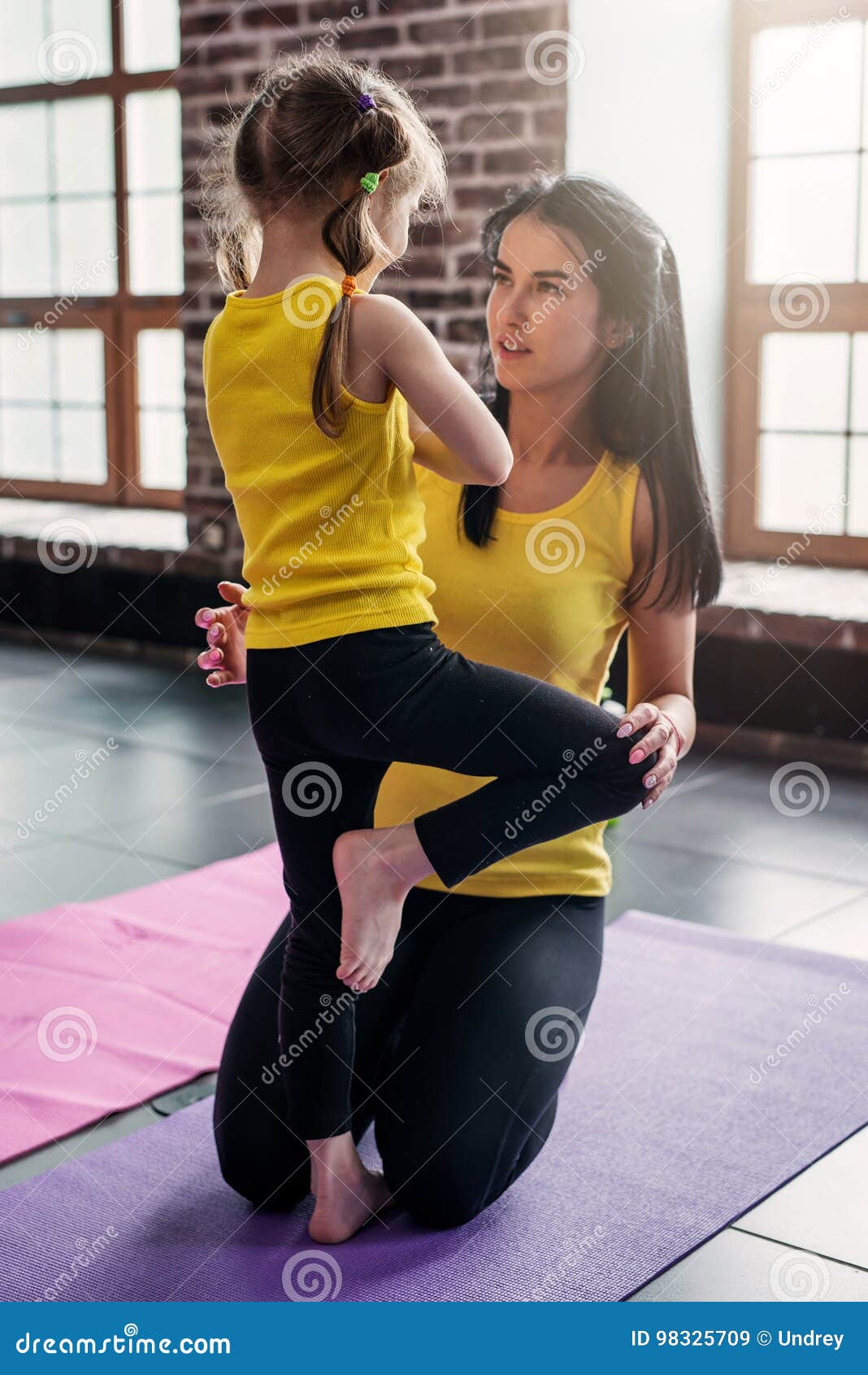 kids yoga teacher teaching girl child doing balance one legged tree pose gym 98325709